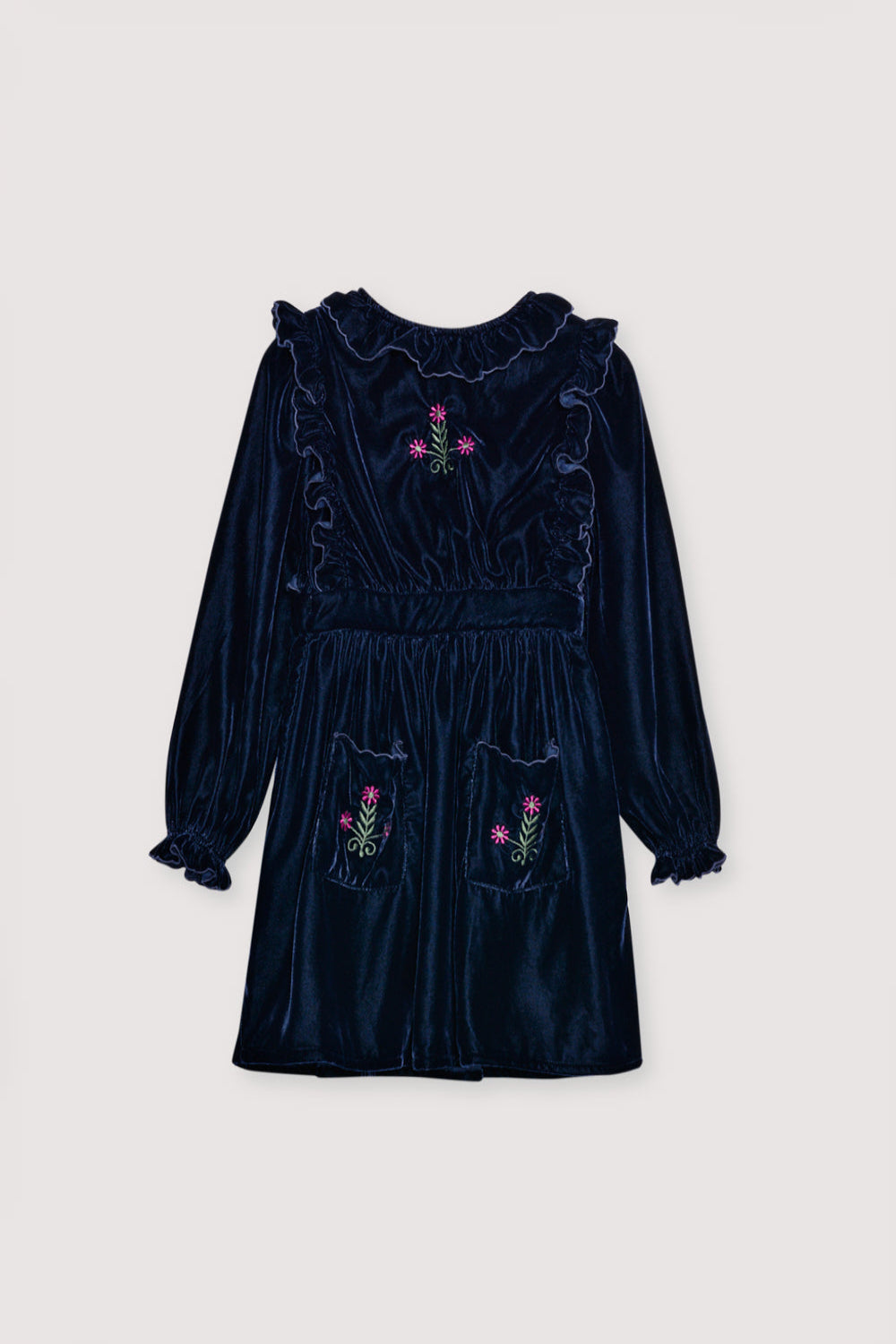 Velour dress with a fitted waist, featuring embroidery detail on the chest and two embroidered pockets on the skirt. It is finished with ruffles at the cuffs and opens at the back with ruffled details. The dress has cotton lining in tone.