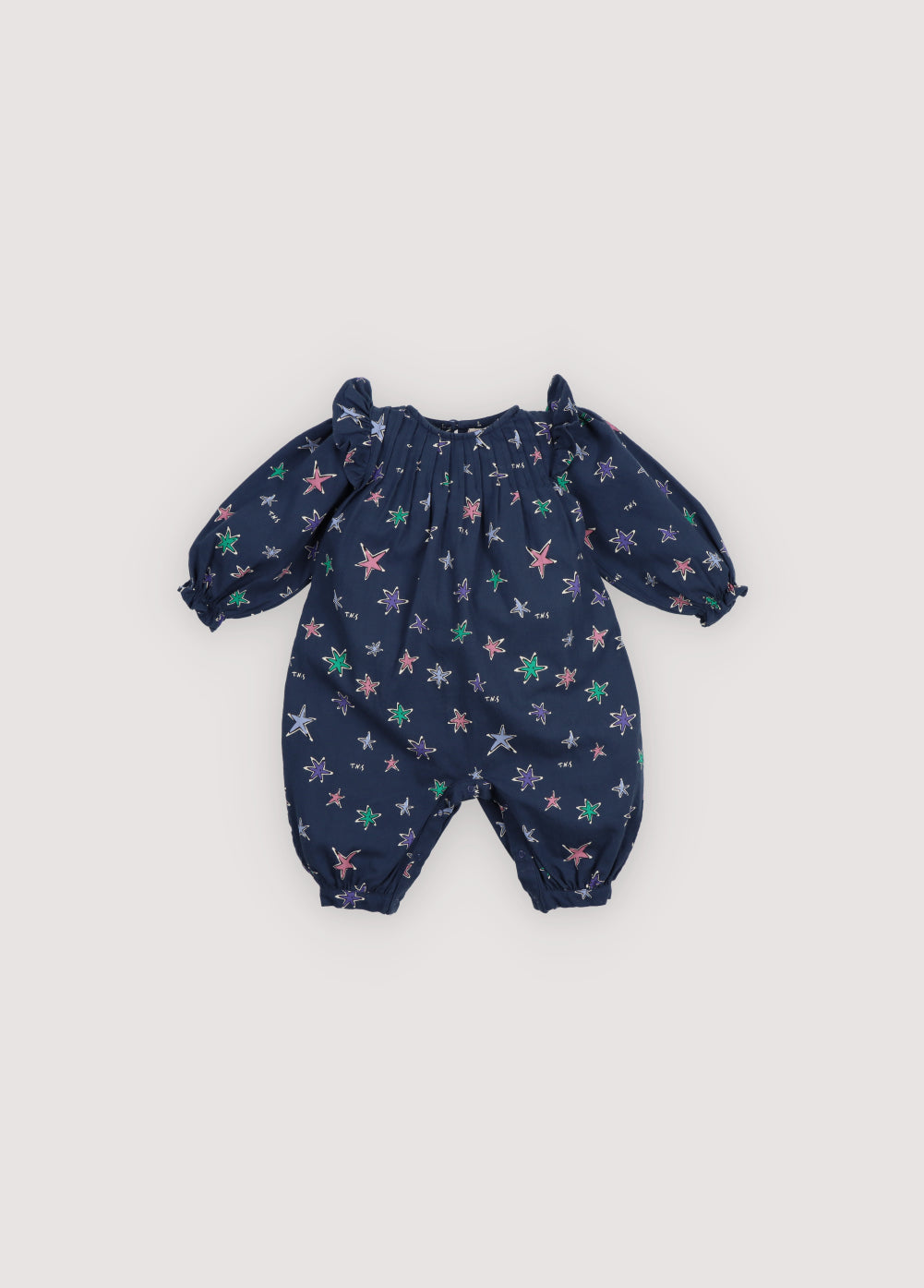 Flannel baby romper with a beautiful and colorful star print. It features pleat details at the front and ruffles on the shoulders. The back opening has tonal snap closures.