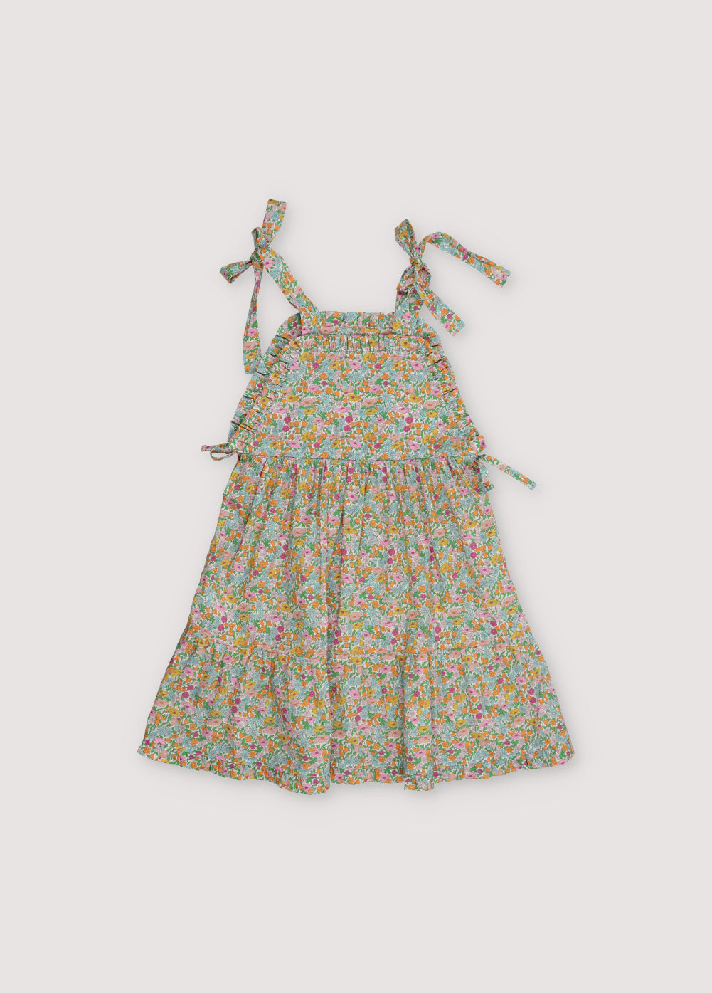 Andreas Dress in Liberty fabric, with front ruffles and a cut to create volume in the ruffle, with bow details on the sides and shoulder straps.