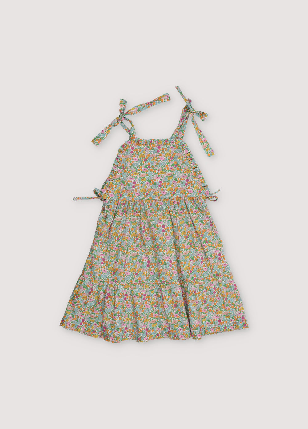 Andreas Dress in Liberty fabric, with front ruffles and a cut to create volume in the ruffle, with bow details on the sides and shoulder straps.