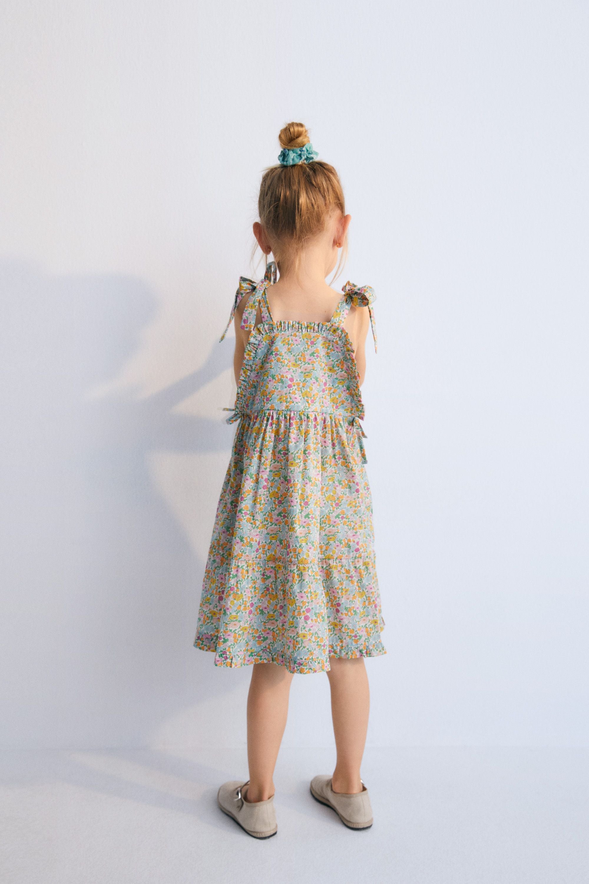 Andreas Dress in Liberty fabric, with front ruffles and a cut to create volume in the ruffle, with bow details on the sides and shoulder straps. Spring Summer Collection. The New Scoiety.
