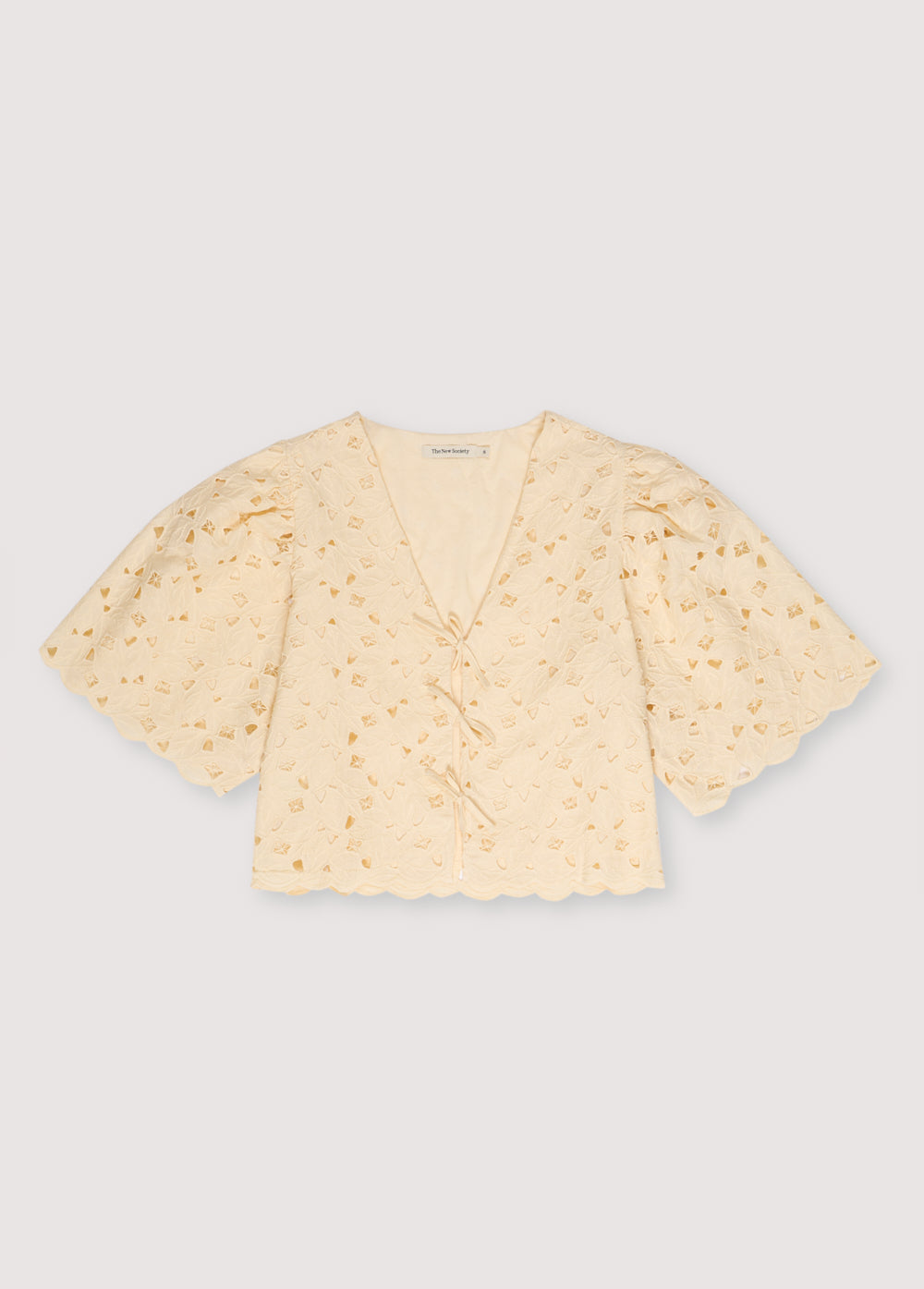 Atenea Woman Blouse in embroidered blend cotton fabric in macadamia color, featuring gathered sleeves, a V-neck, and closure with two bows in the center. Spring Summer Collection. The New Society