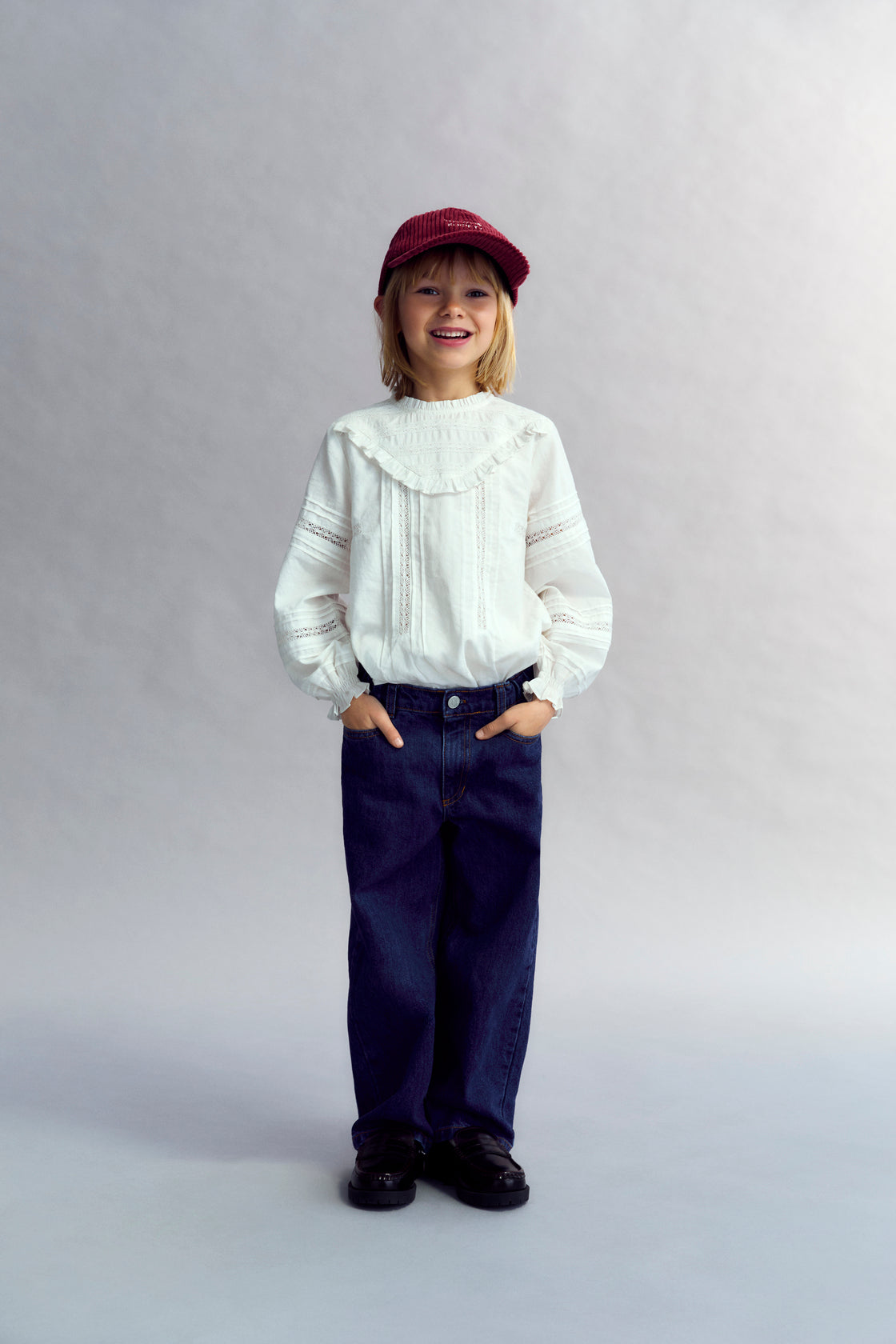 Romantic-style blouse with a front yoke detail in lace and a ruffle finish, along with lace details on the sleeves. It features a round neckline with a small ruffle trim and a back opening with a button closure.