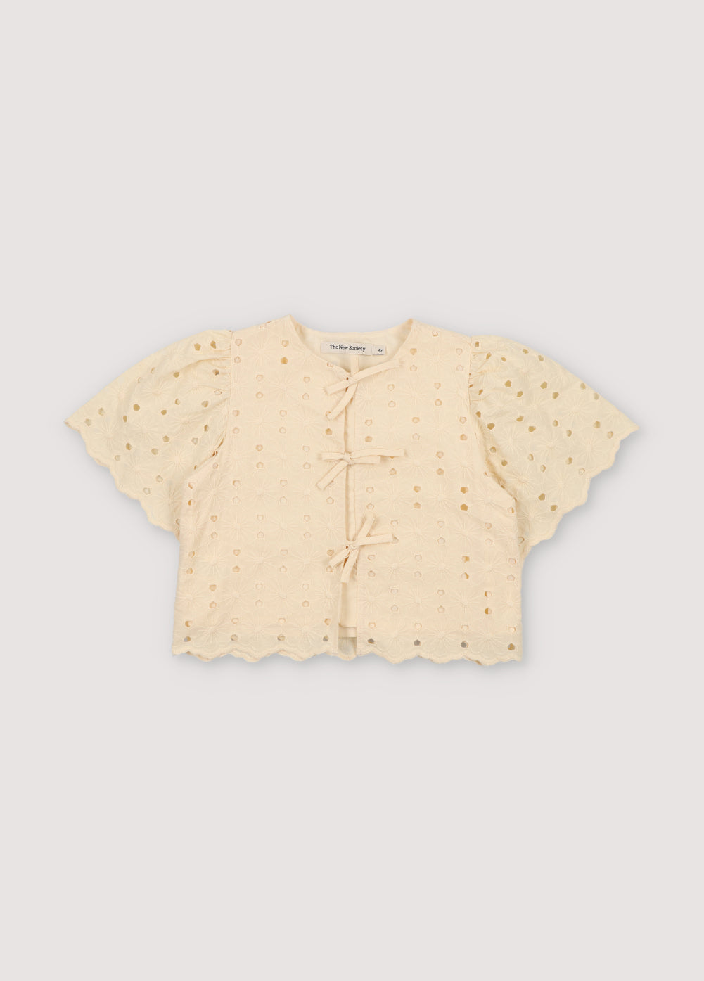 Creta Blouse in embroidered blend cotton fabric in macadamia color, featuring gathered sleeves, a high neckline, and central bow closure. New Collection Kids