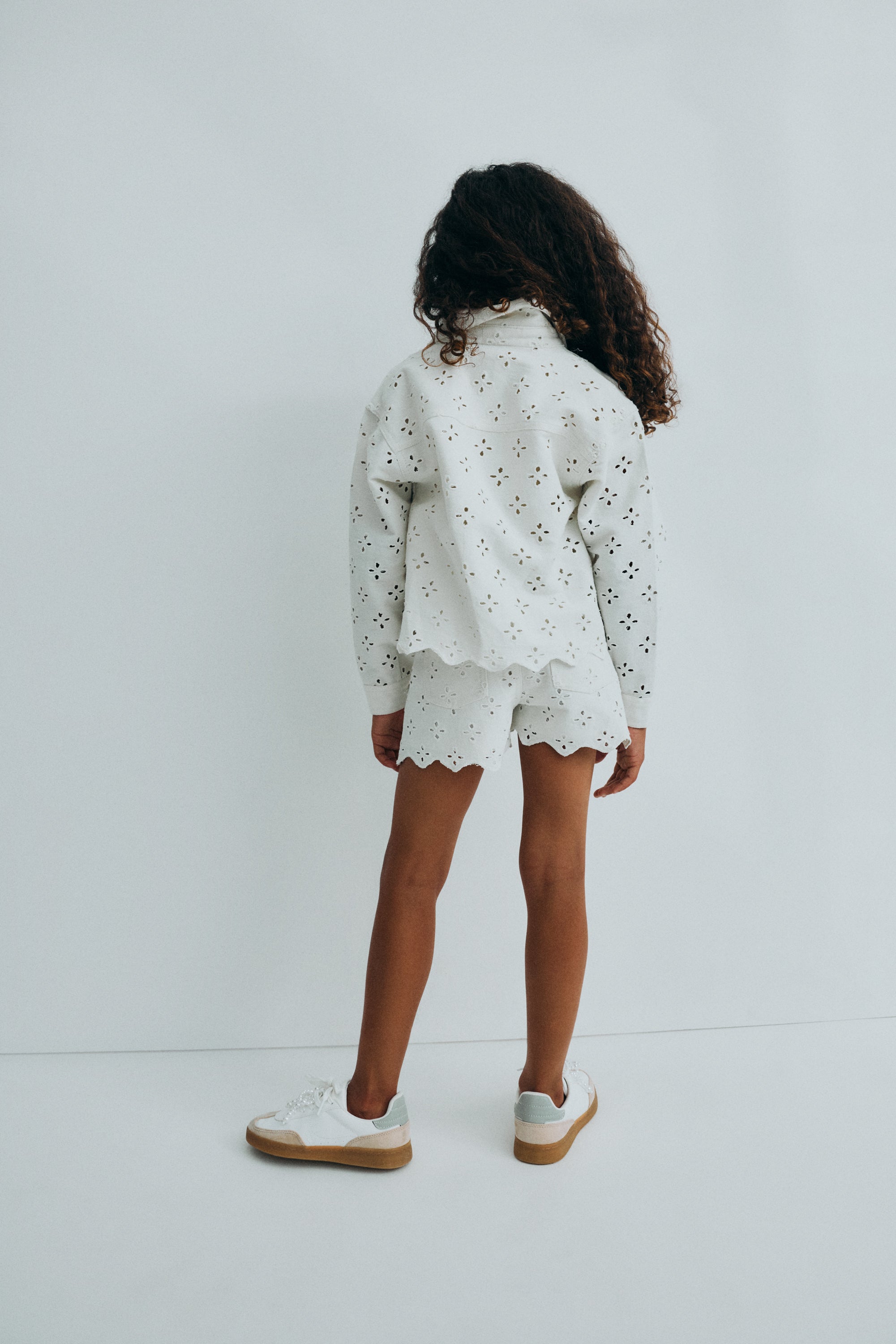 前開き、サイドとバックポケット付きのデニムショートパンツ。繊細なデニム生地で作られ、全面に刺繍が施されています。