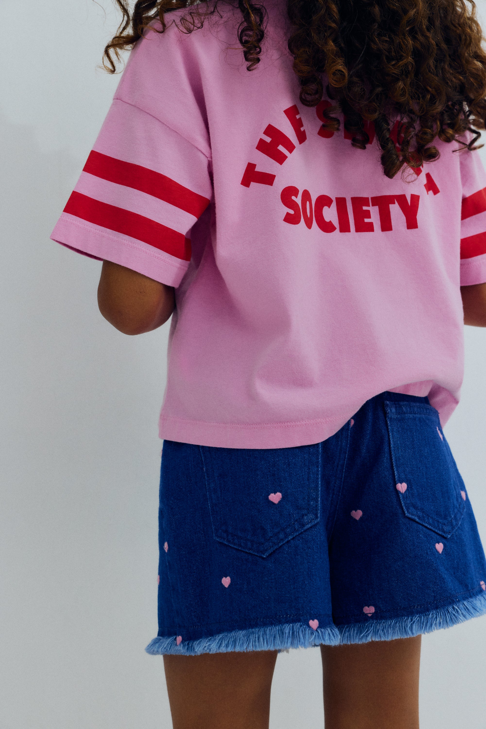 Crop style t-shirt in soft cotton, featuring contrasting branded embroidery, a stripe print on the sleeve, and a collection print on the back for a playful, modern look.