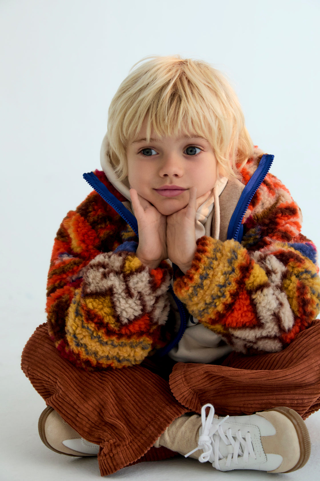 Child wearing a colorful knit sweater with a white background