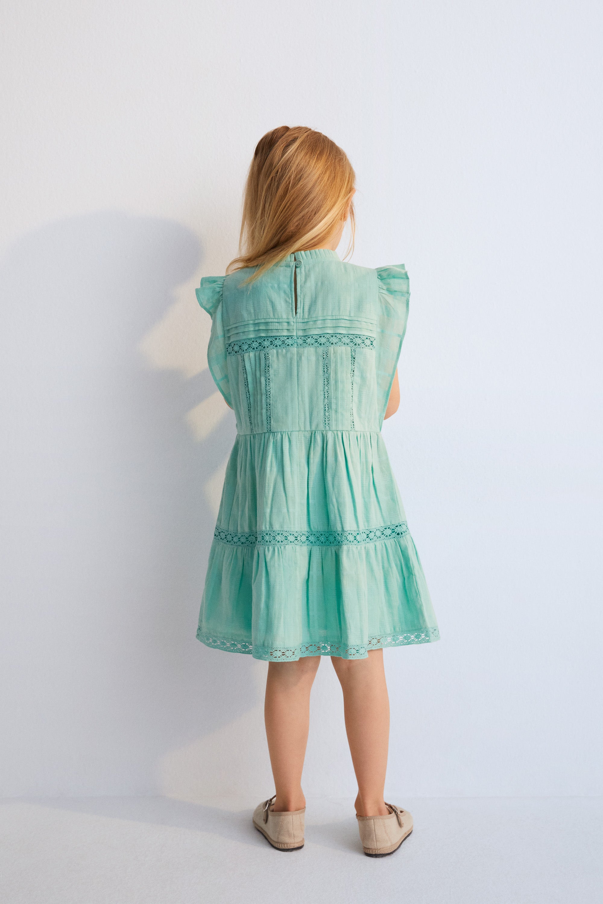 Robe courte en tissu jacquard et détails en dentelle. Il présente des volants sur les manches et une ouverture au dos avec bouton en nacre.