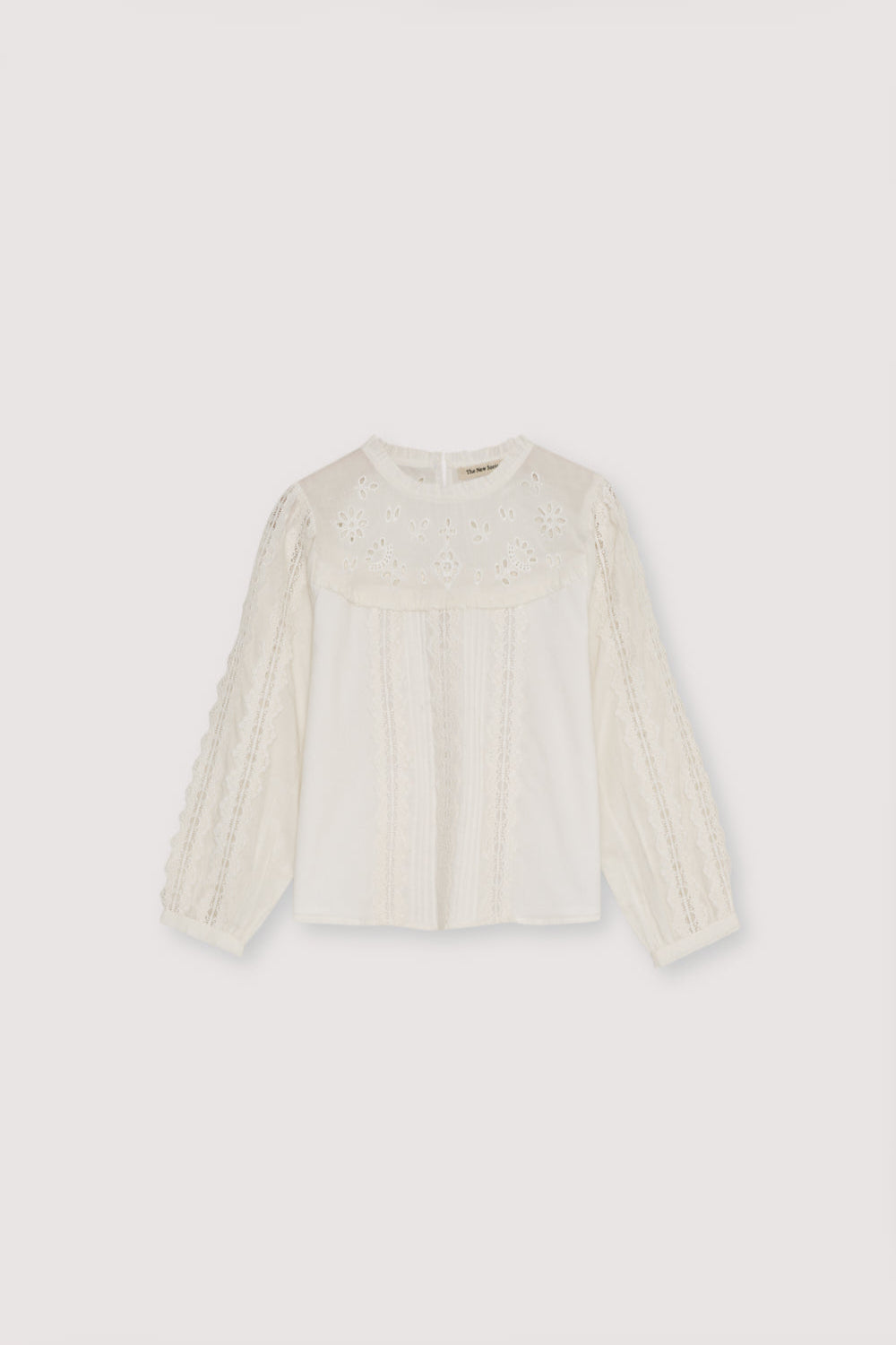 Cotton voile blouse with embroidered yoke detail and ruffles, and lace detailing on the body and sleeves. It features a back keyhole opening with a tone-on-tone button.