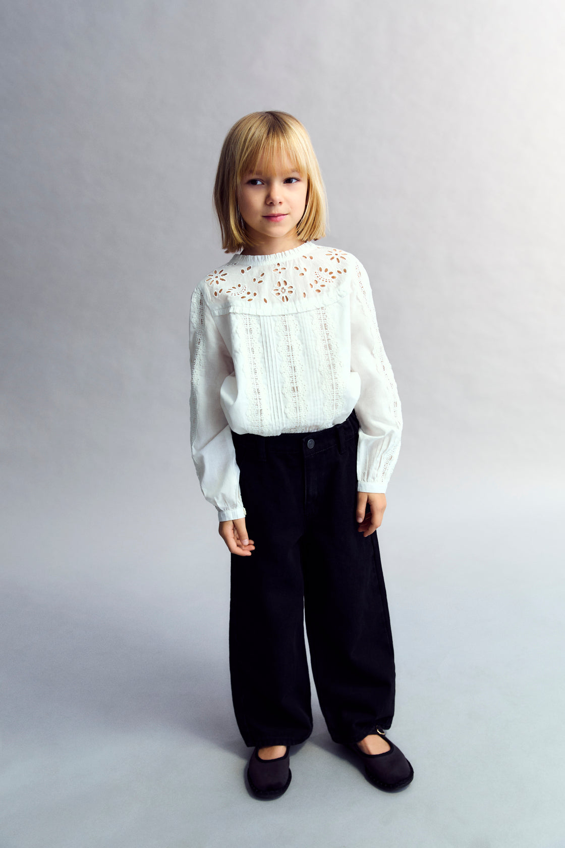 Cotton voile blouse with embroidered yoke detail and ruffles, and lace detailing on the body and sleeves. It features a back keyhole opening with a tone-on-tone button.