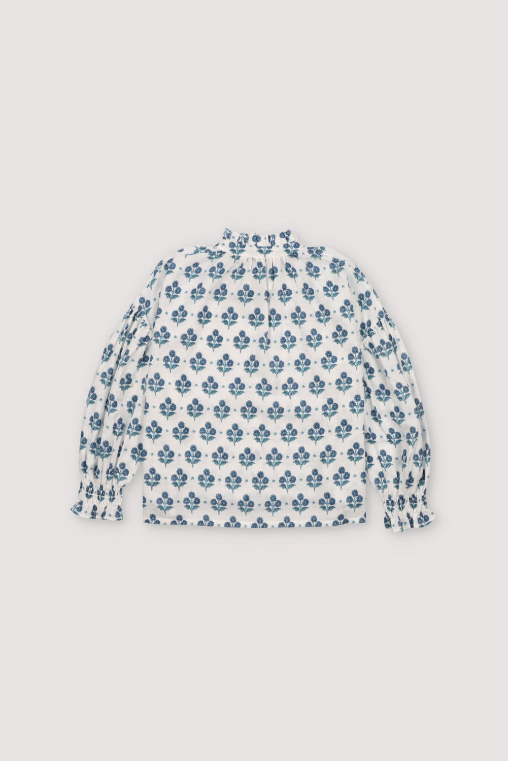 Eleni Blouse in 100% cotton muslin fabric with our hyacinth print. It features a high neckline with a ruffle and adjustable bow, short sleeves with smocking and a decorative ruffle.