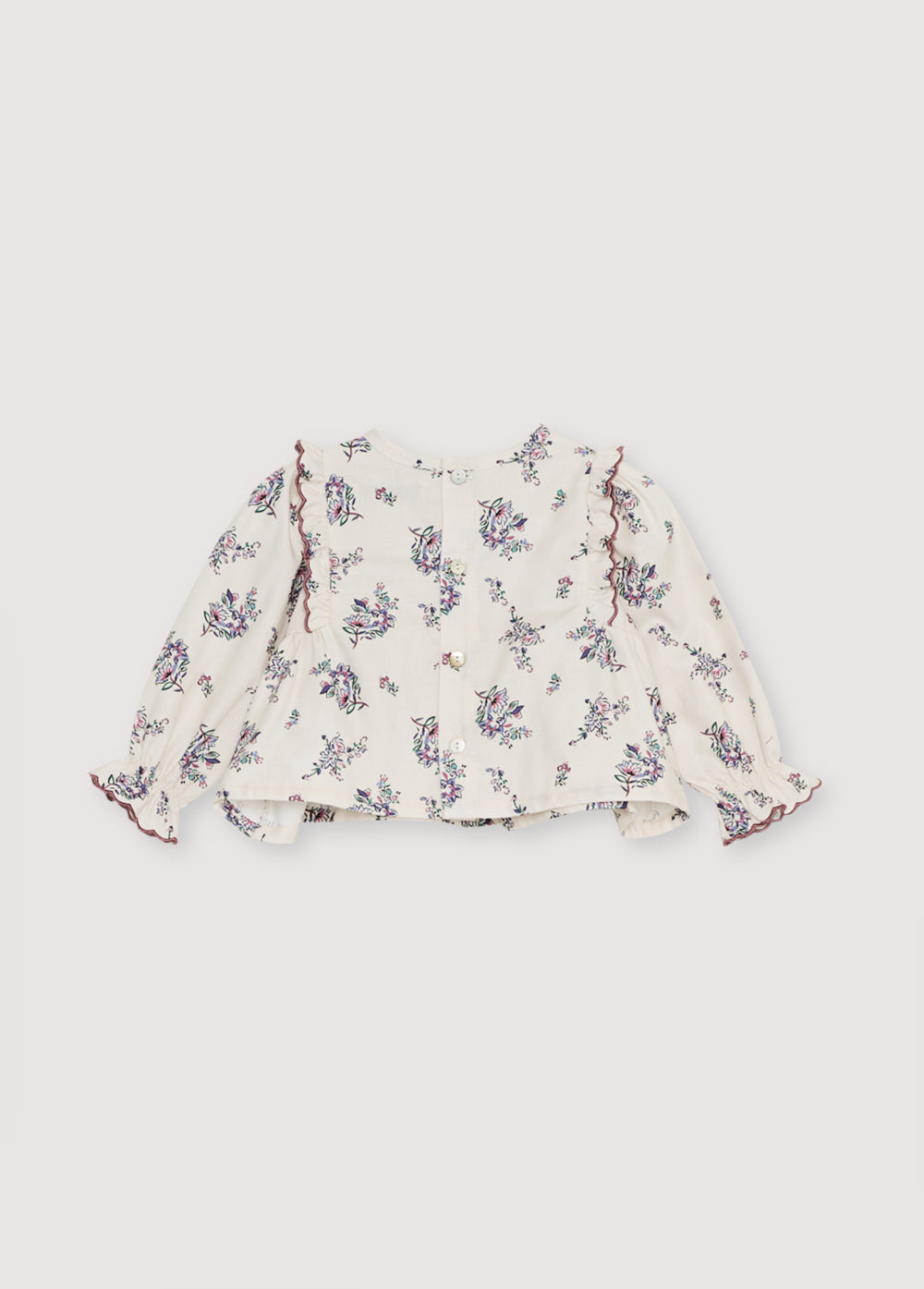 Flannel blouse with a beautiful floral print and a front yoke with ruffles. It features delicate curved embroidery finishes that make it special. It opens at the back with snaps closure.