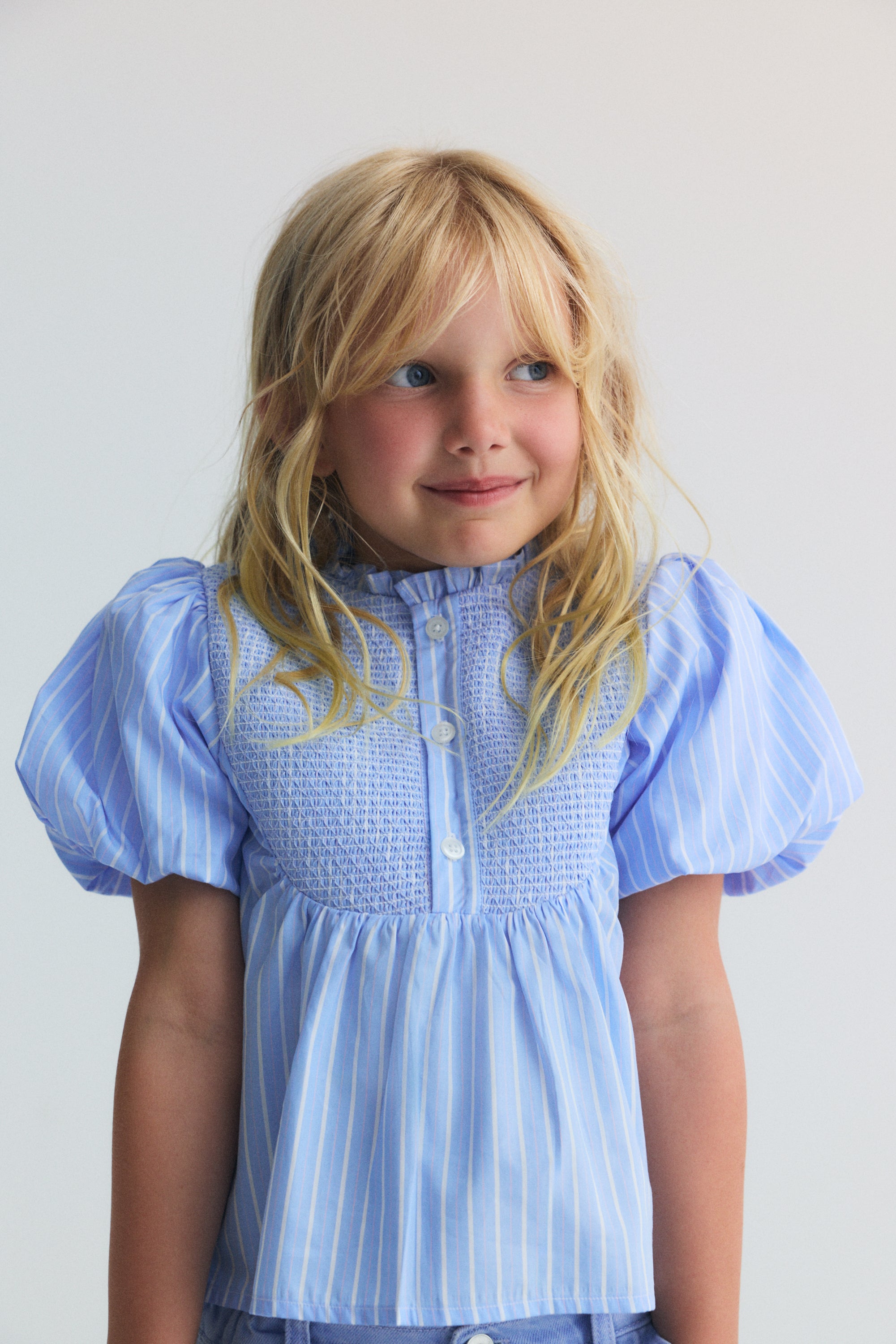 Blue striped blouse featuring a beautiful smocked front with button opening and original puff sleeves, making it a truly special and feminine piece.