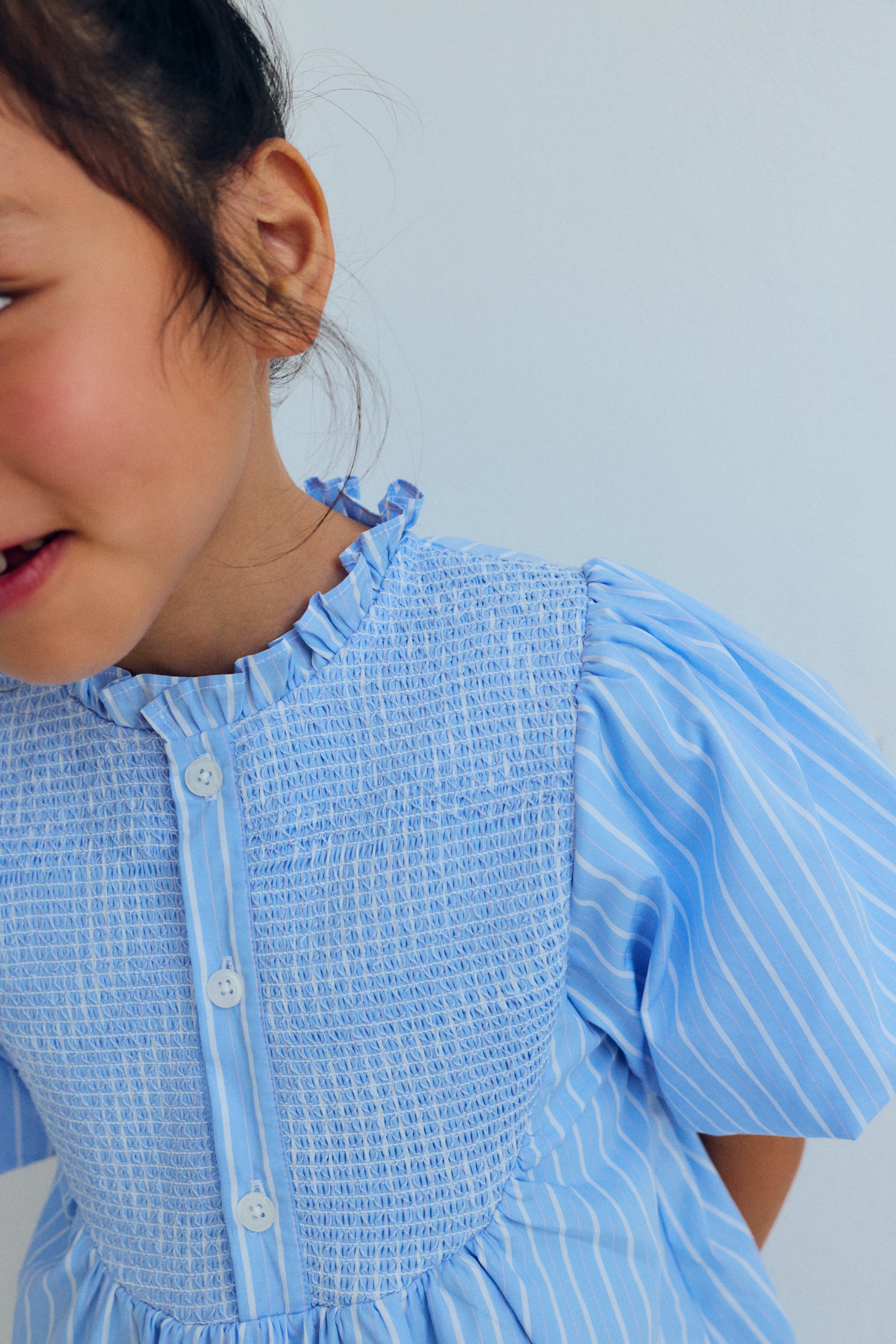 Short striped cotton dress featuring a delicate smocked front, button opening, and stunning puff sleeves that make it a truly special piece.