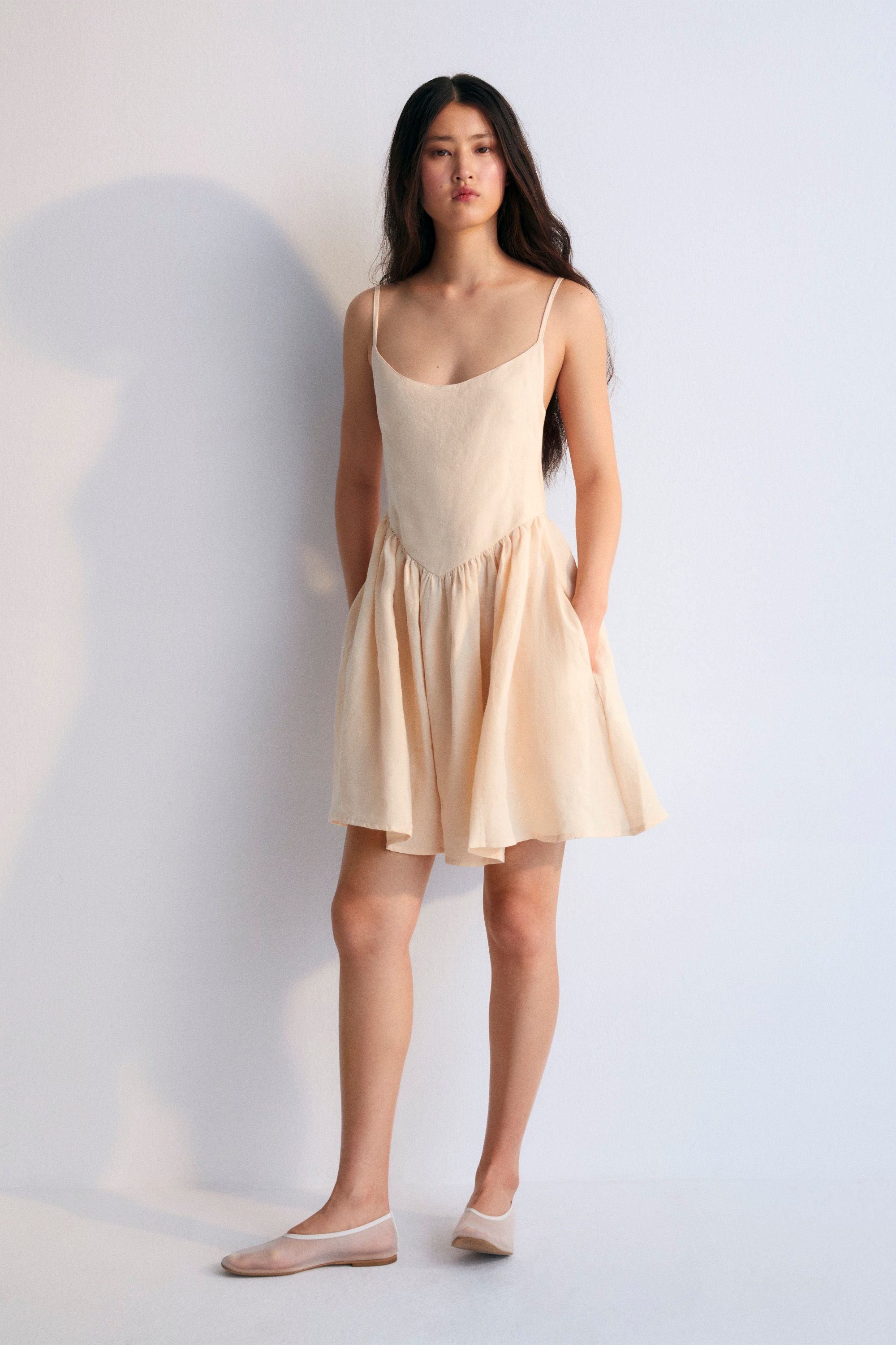 Hera Woman Short Dress in 100% linen, available in three colors: caviar, macadamia, and palm. Square neckline, straps with fasteners, and a short skirt with volume. Spring Summer Collection. The New Society.
