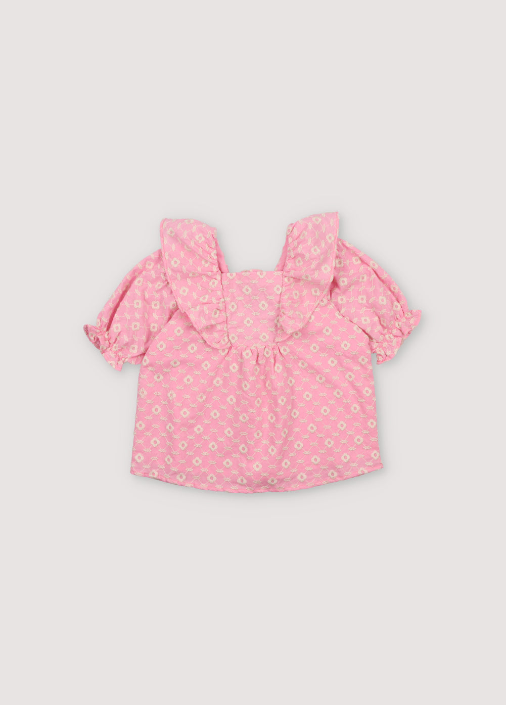 Isidora Blouse in hibiscus voile fabric with macadamia cot-pes embroidery. Square neckline, side ruffles, and puffed short sleeves.