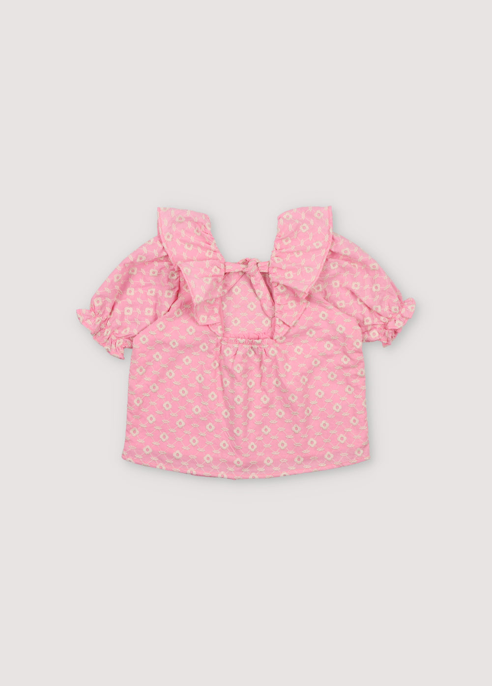 Isidora Blouse in hibiscus voile fabric with macadamia cot-pes embroidery. Square neckline, side ruffles, and puffed short sleeves.