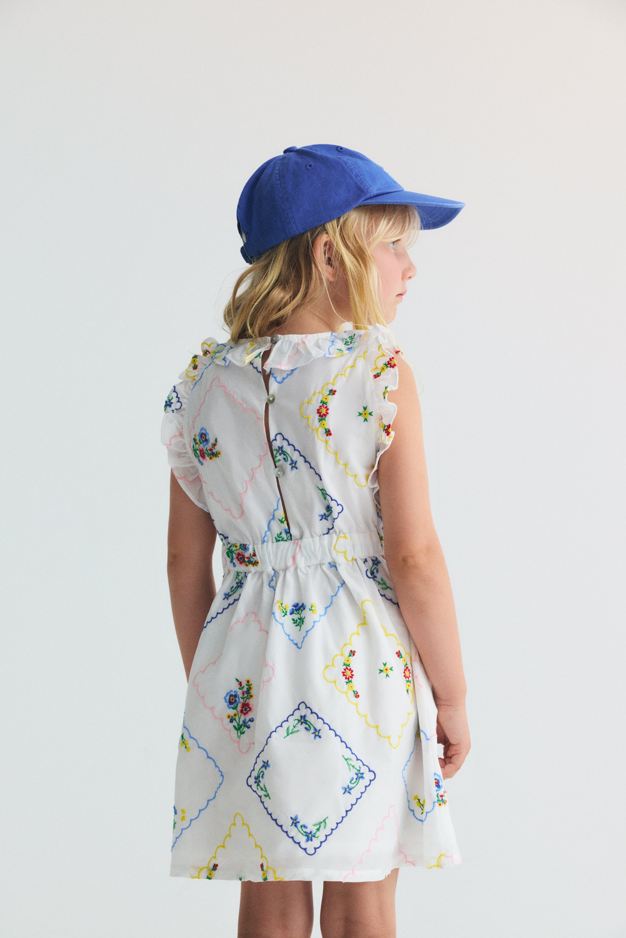 Cette robe 100% coton, fabriquée au Portugal, allie douceur et style avec de charmantes broderies florales colorées partout.