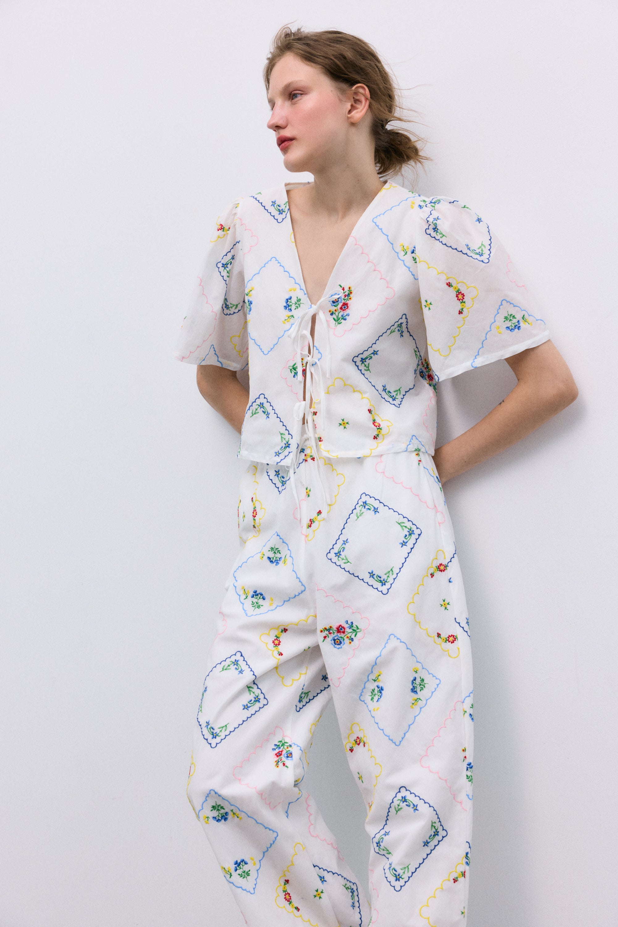 Délicate et charmante, cette blouse 100 % coton, fabriquée au Portugal, présente d'exquises broderies florales multicolores partout.