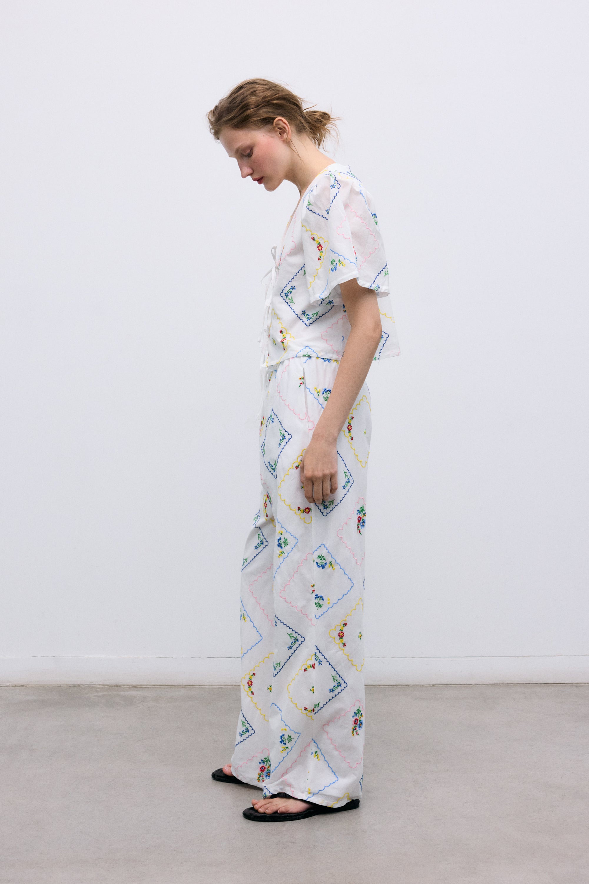 Délicate et charmante, cette blouse 100 % coton, fabriquée au Portugal, présente d'exquises broderies florales multicolores partout.