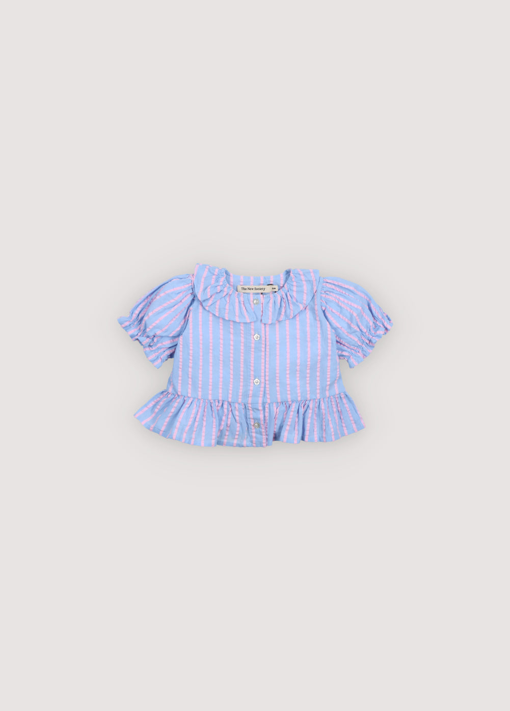 Kythira Baby Blouse in 100% cotton striped fabric with cut details and ruffles at the hem, ruffled neckline, puffed short sleeves, and mother-of-pearl flower-shaped buttons. Spring Summer Collection. The New Society.