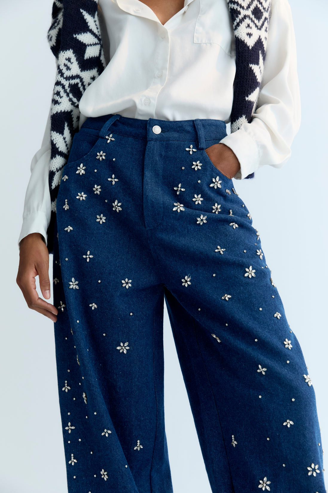 Wide-leg denim pant with delicate hand-applied crystal details at the front. It features patch pockets at the back and TNS embroidery on the waistband.