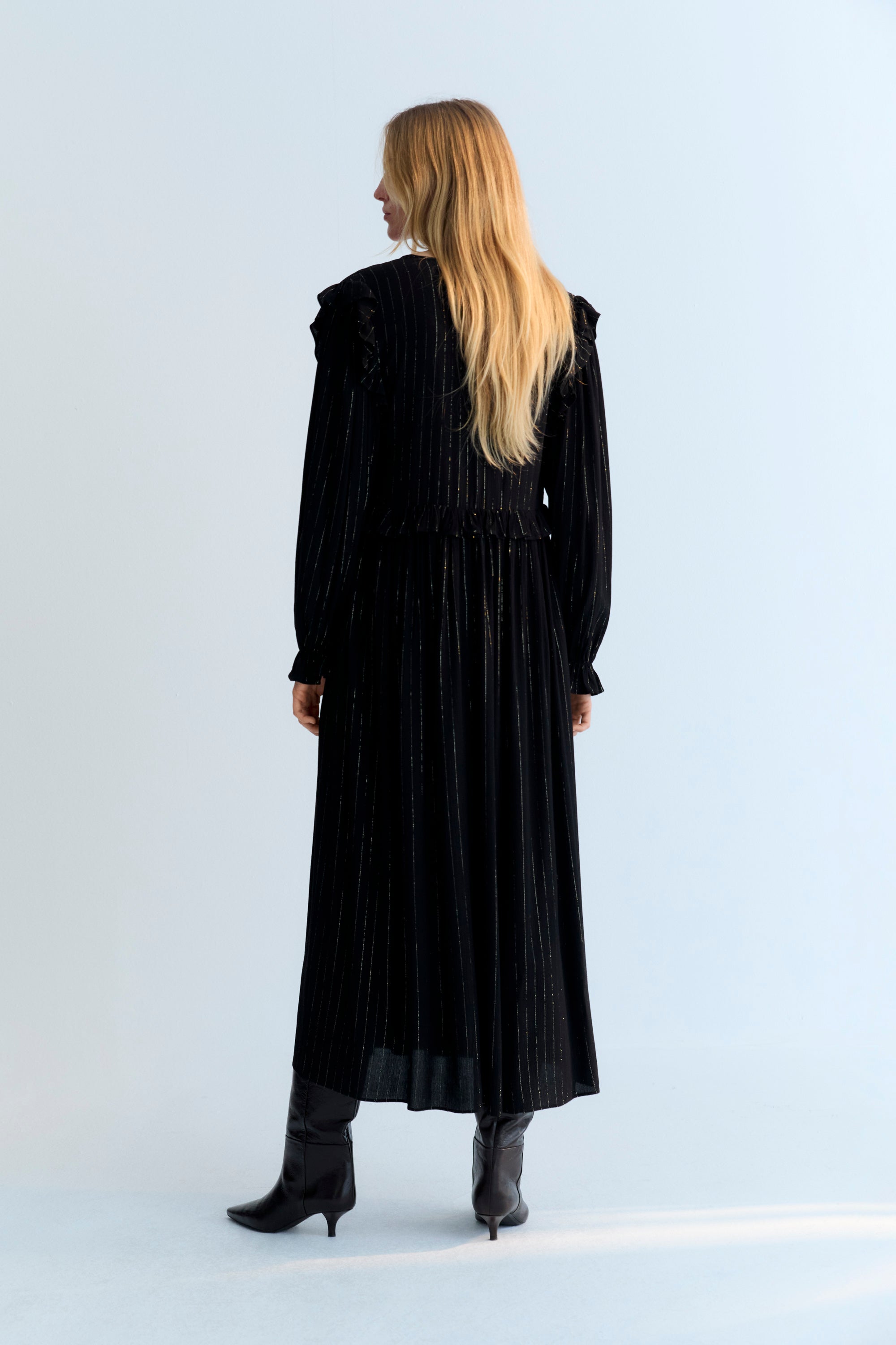 Long and flowy viscose dress with lurex in black color. It features a front opening with a bow and button closure, and a ruffle detail on the shoulders.