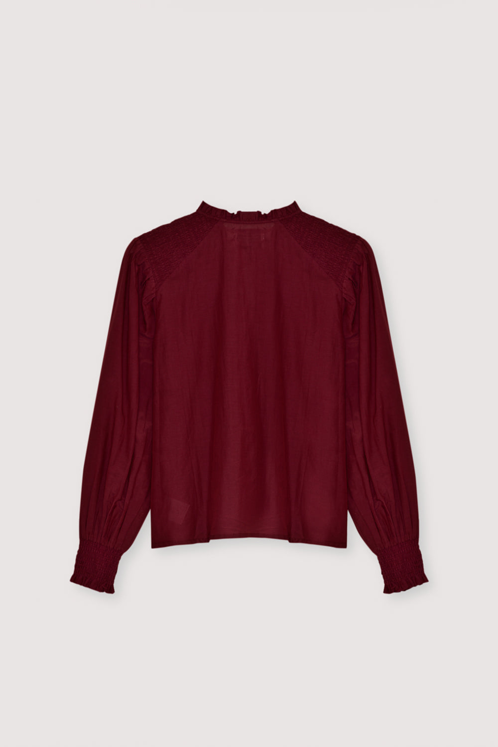 A refined cambric blouse crafted from a lightweight, high-quality fabric. Designed with delicate smocking on the shoulders and cuffs, it adds subtle texture and an elegant feminine touch. The front features a clean hidden placket for a sleek, minimal finish. Available in plum fantasy color, perfect for effortless everyday styling or polished looks.
