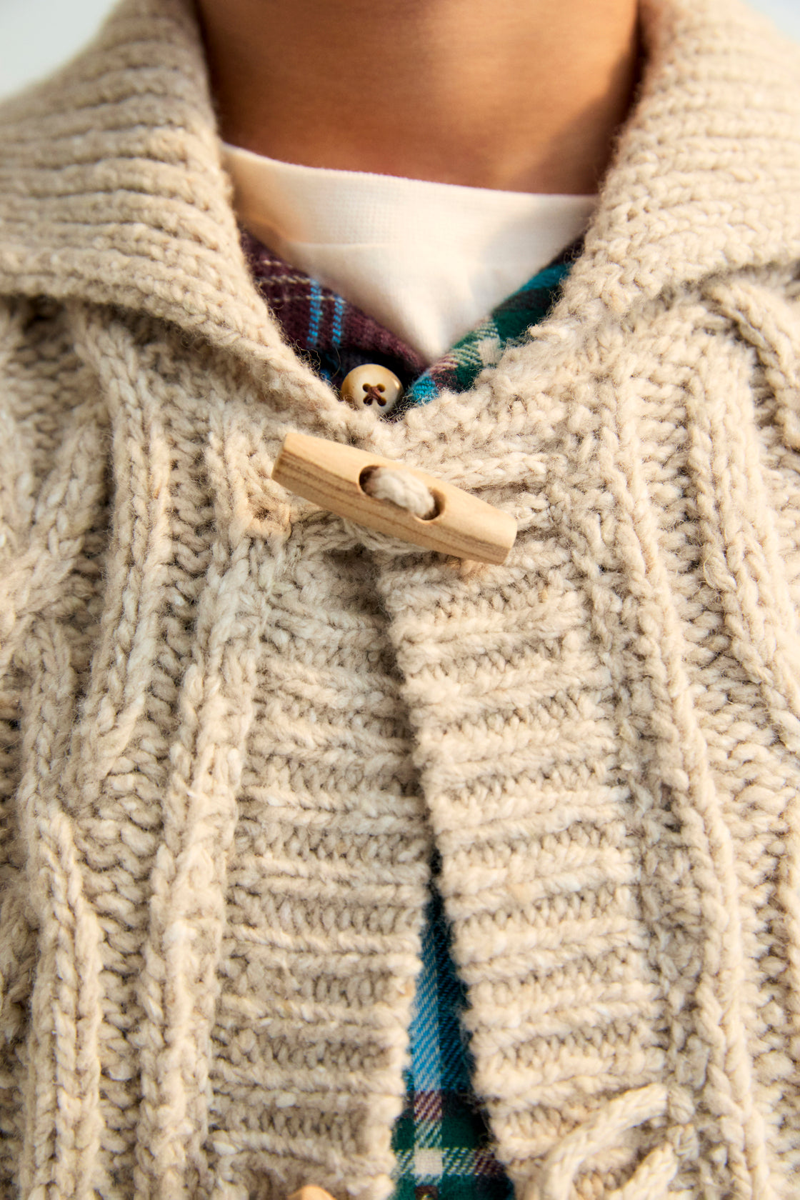 Knitted cardigan with a ribbed collar, cuffs, and hem. Features a front opening with wooden toggles. Made with recycled wool.