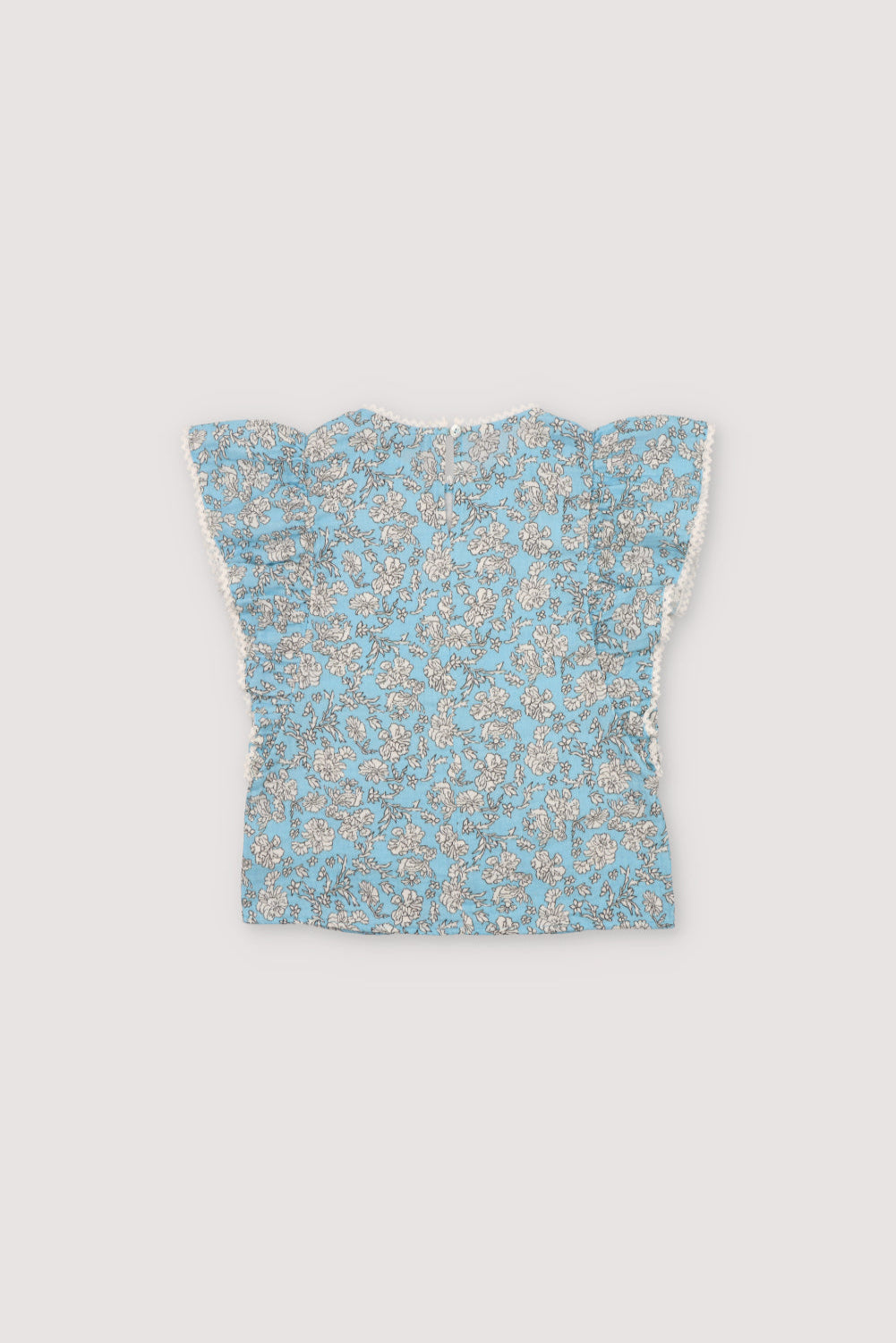 Melina Blouse in 100% cotton muslin with our peony powder blue print. The blouse features a ruffle from the shoulder to the hem, a high neckline, and lace detail on the neckline and ruffle.