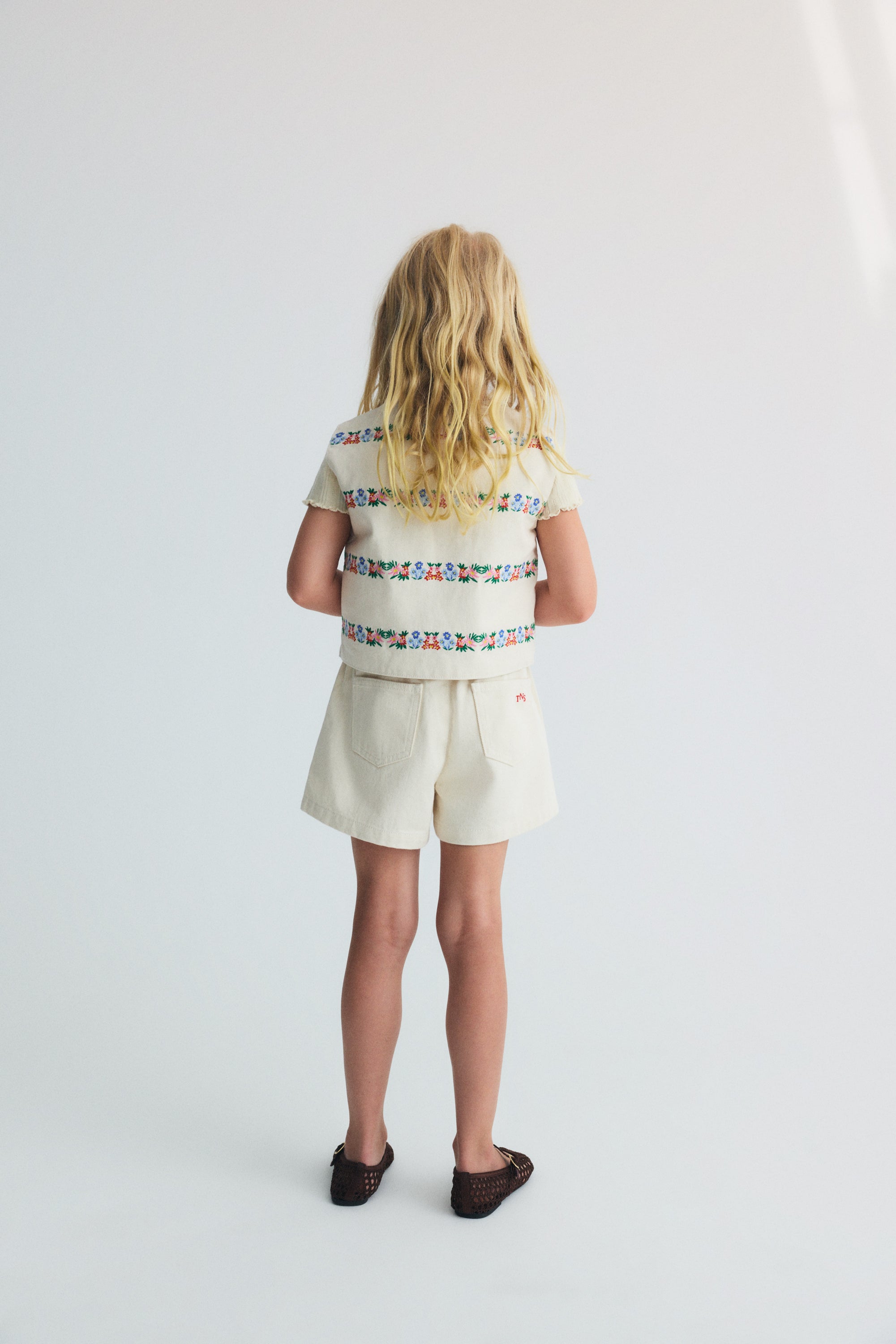 Gilet matelassé pour enfants confectionné en denim de coton BCI, avec de délicats et magnifiques détails de broderie sur le devant et dans le dos.