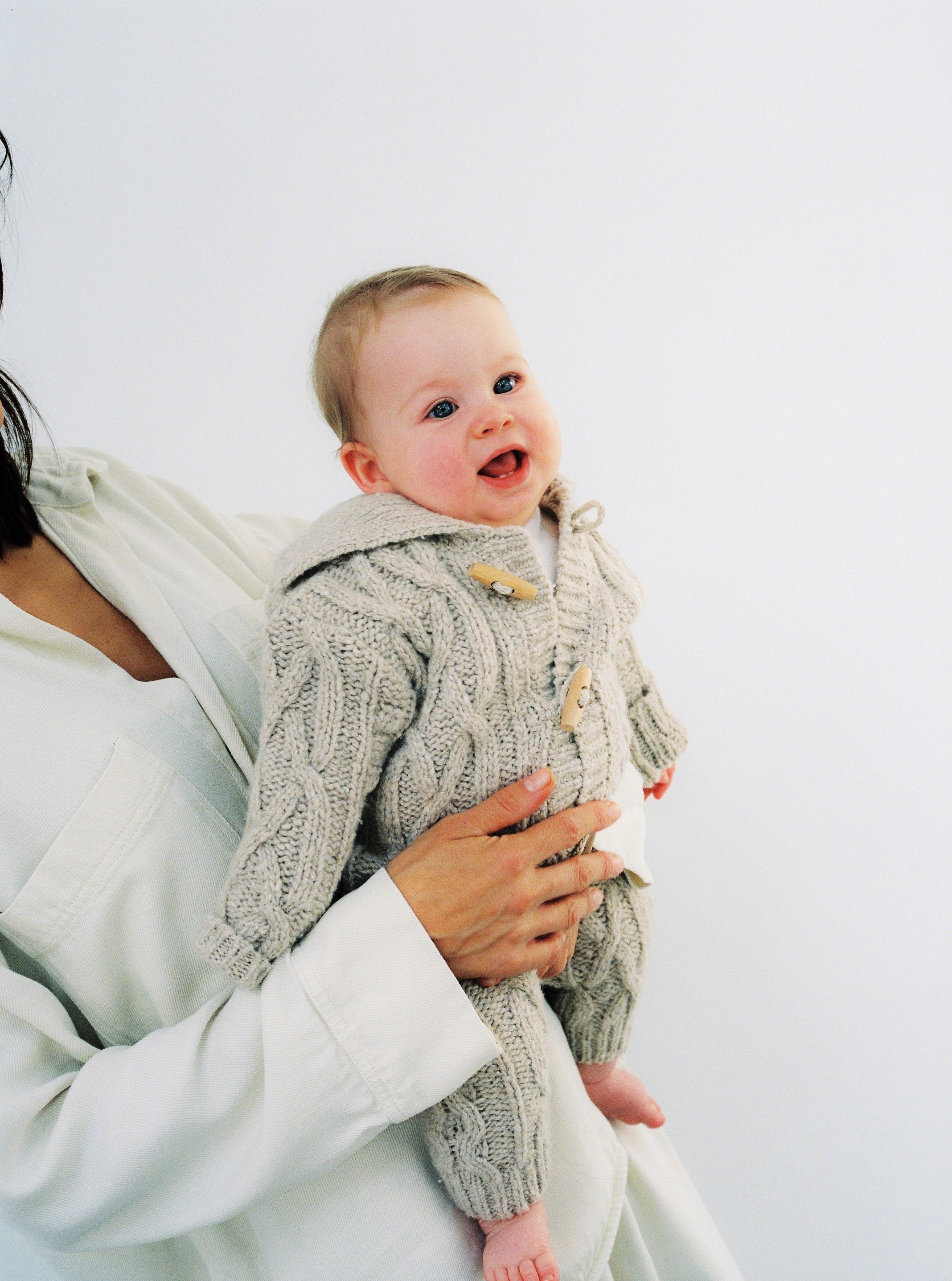 Knitted cardigan with a ribbed neckline, cuffs, and hem. Features a front opening with wooden toggles. Comes with matching knit pants to complete the look. Made with high-quality recycled materials.