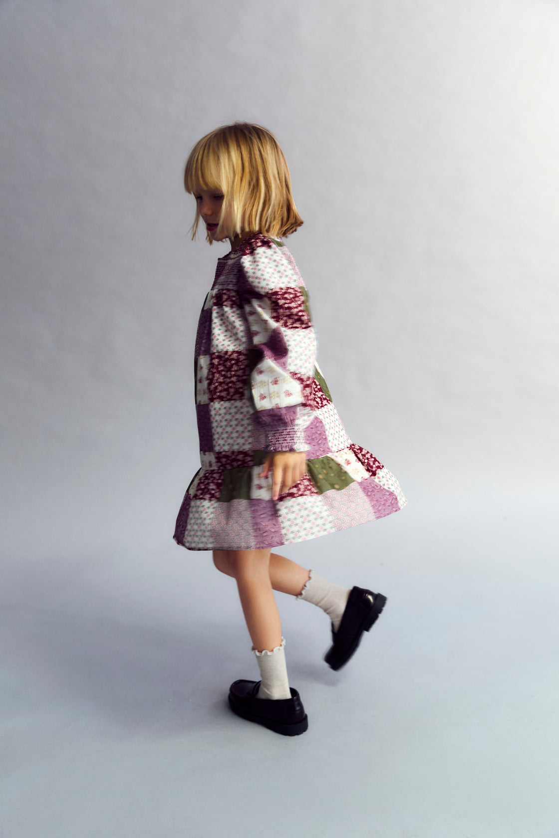 This charming dress features a unique patchwork print, puffed sleeves, and a ruffled skirt.