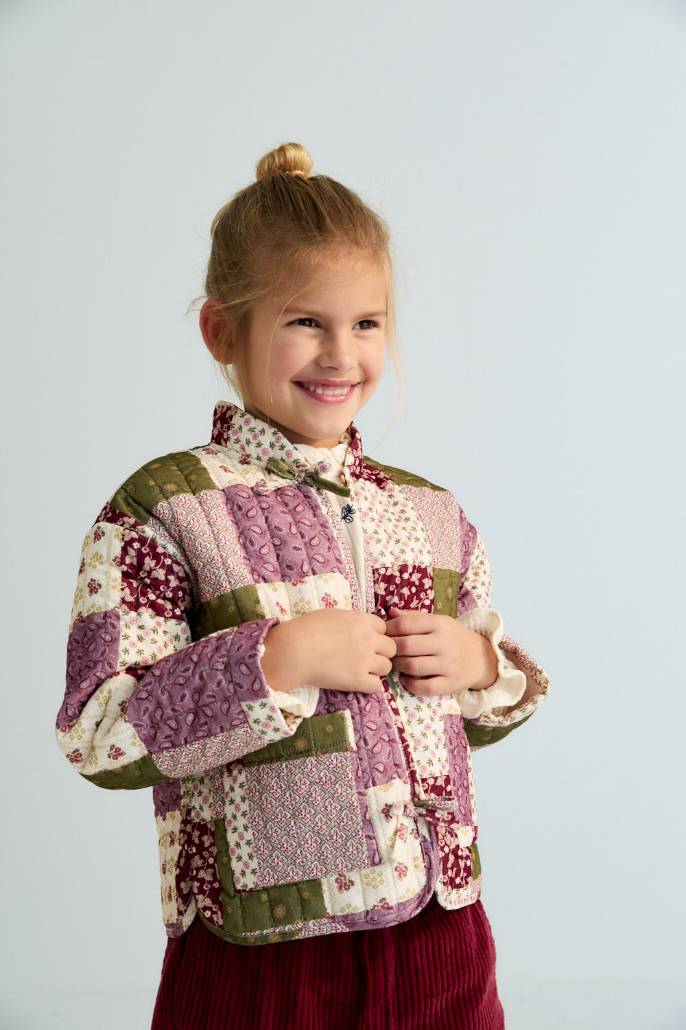 Quilted micro-corduroy jacket with a unique patchwork print, featuring a tie closure and button at the front.