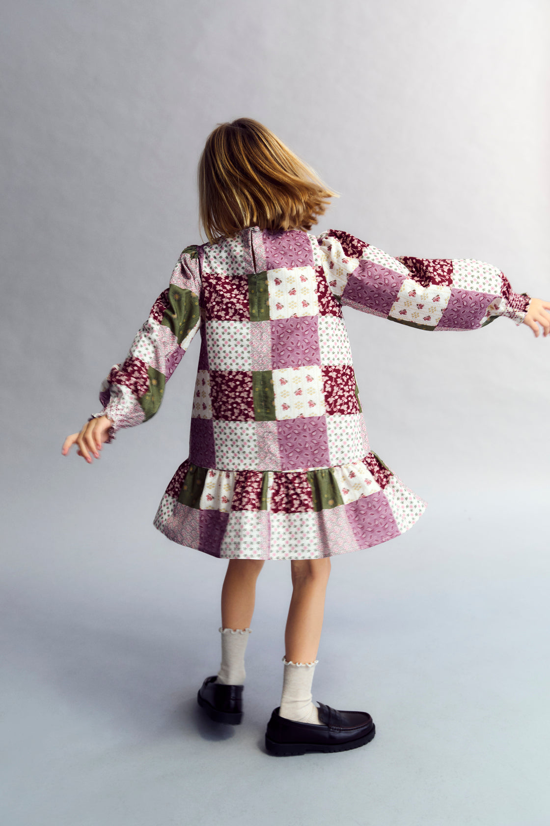 This charming dress features a unique patchwork print, puffed sleeves, and a ruffled skirt.