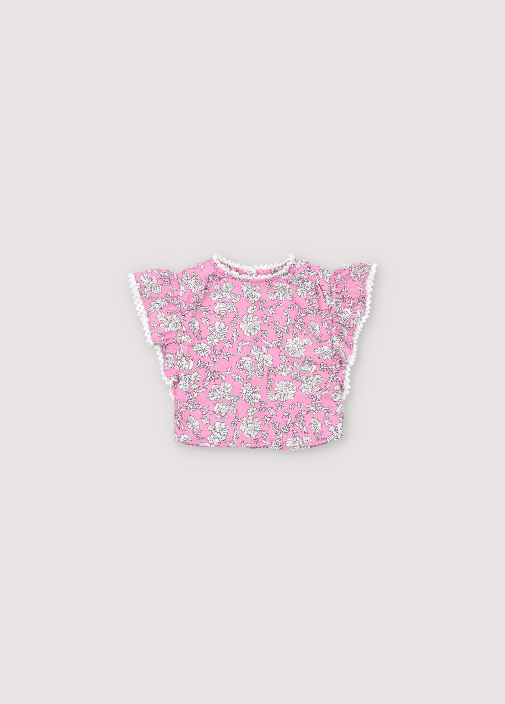 Melina Baby Blouse in 100% cotton muslin with our peony hibiscus print. The blouse features a ruffle from the shoulder to the hem, a high neckline, and lace detail on the neckline and ruffle. Spring Summer Collection. The New Society.
