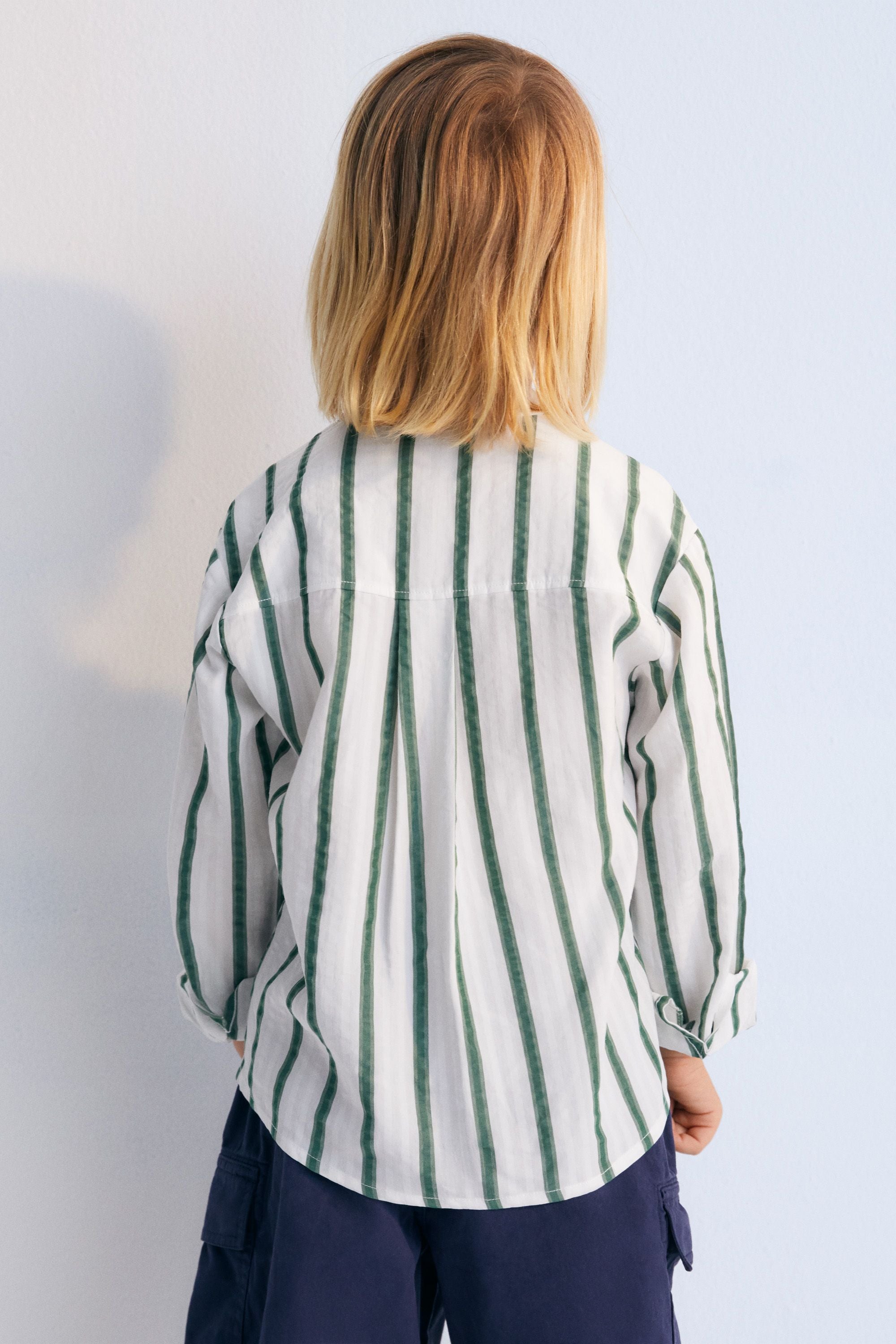 Milos Boy Shirt in 100% Tencel striped fabric, long sleeves, Mandarin collar, and chest pocket with TNS logo detail matching the stripe color. Spring Summer Collection. The New Society.