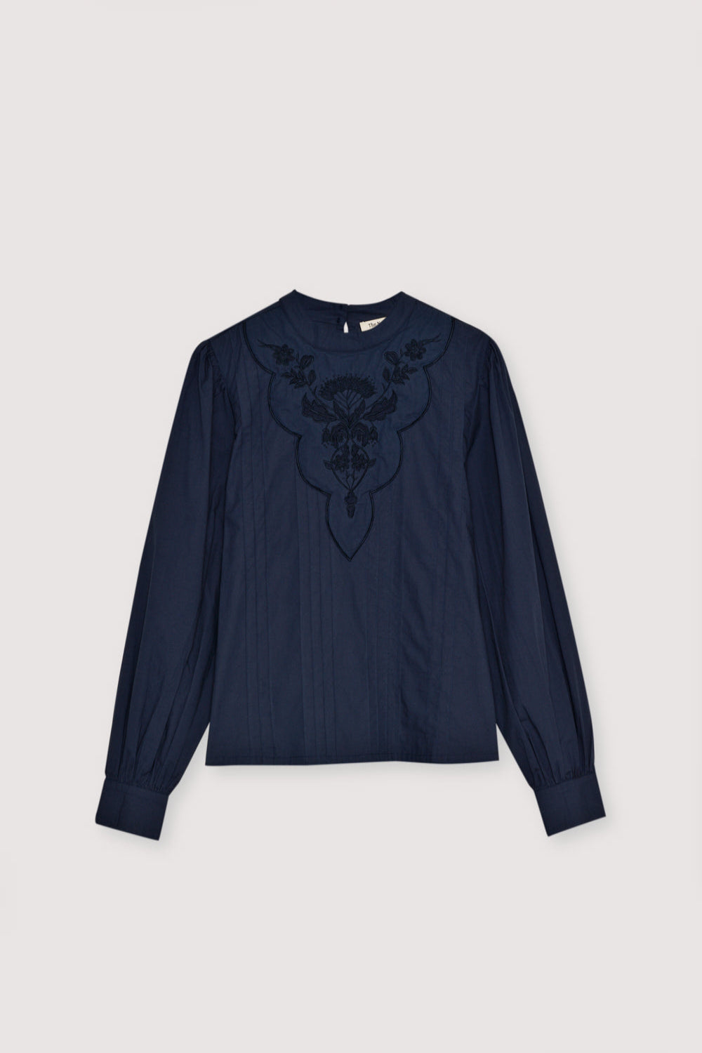 Poplin blouse with embroidered detail and pleats at the front. It features button cuffs and gathered sleeves at the shoulders. The blouse opens at the back with a keyhole and button.