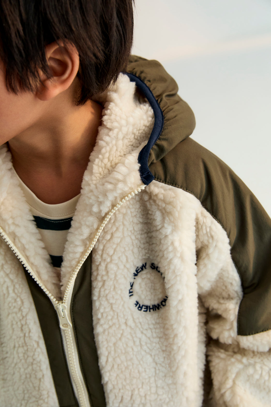 Hoodie-style outerwear with contrasting outerwear fabric. It features a front kangaroo pocket, matching zipper, and contrast embroidery on the chest. It also has a hood and piping details on the finishes.