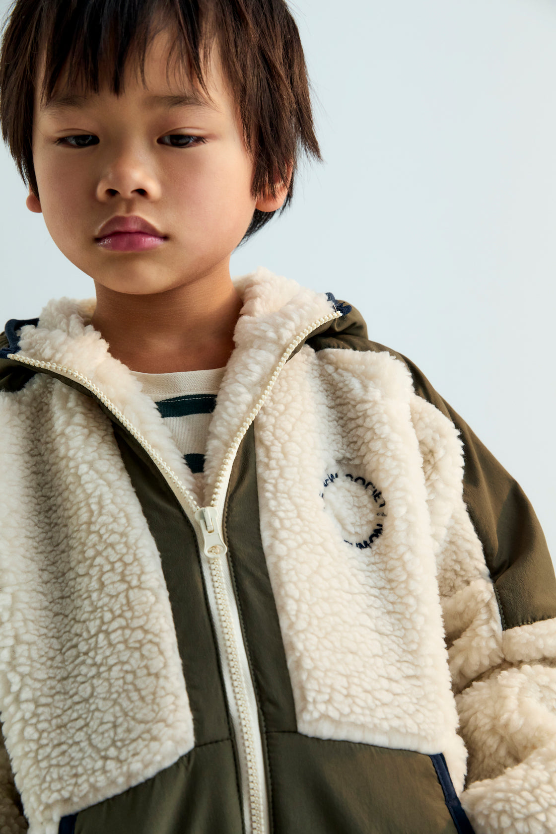 Hoodie-style outerwear with contrasting outerwear fabric. It features a front kangaroo pocket, matching zipper, and contrast embroidery on the chest. It also has a hood and piping details on the finishes.