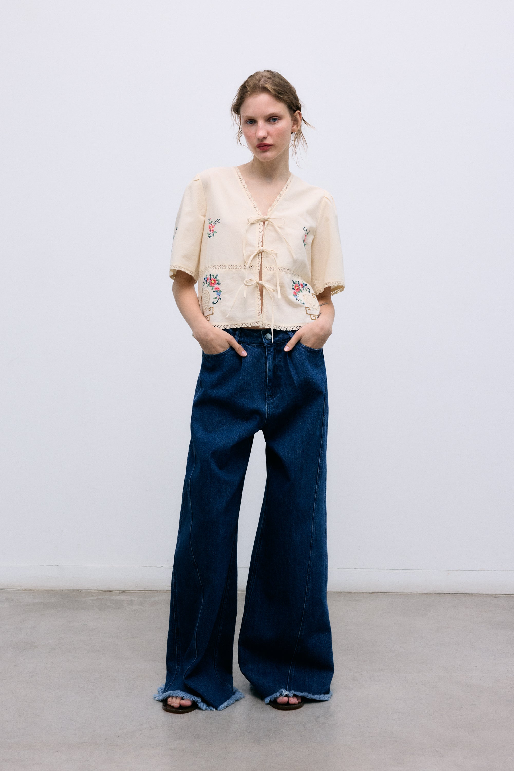 Crafted from soft 100% cotton, this blouse features a flattering V-neckline and a front opening with delicate tie closures.