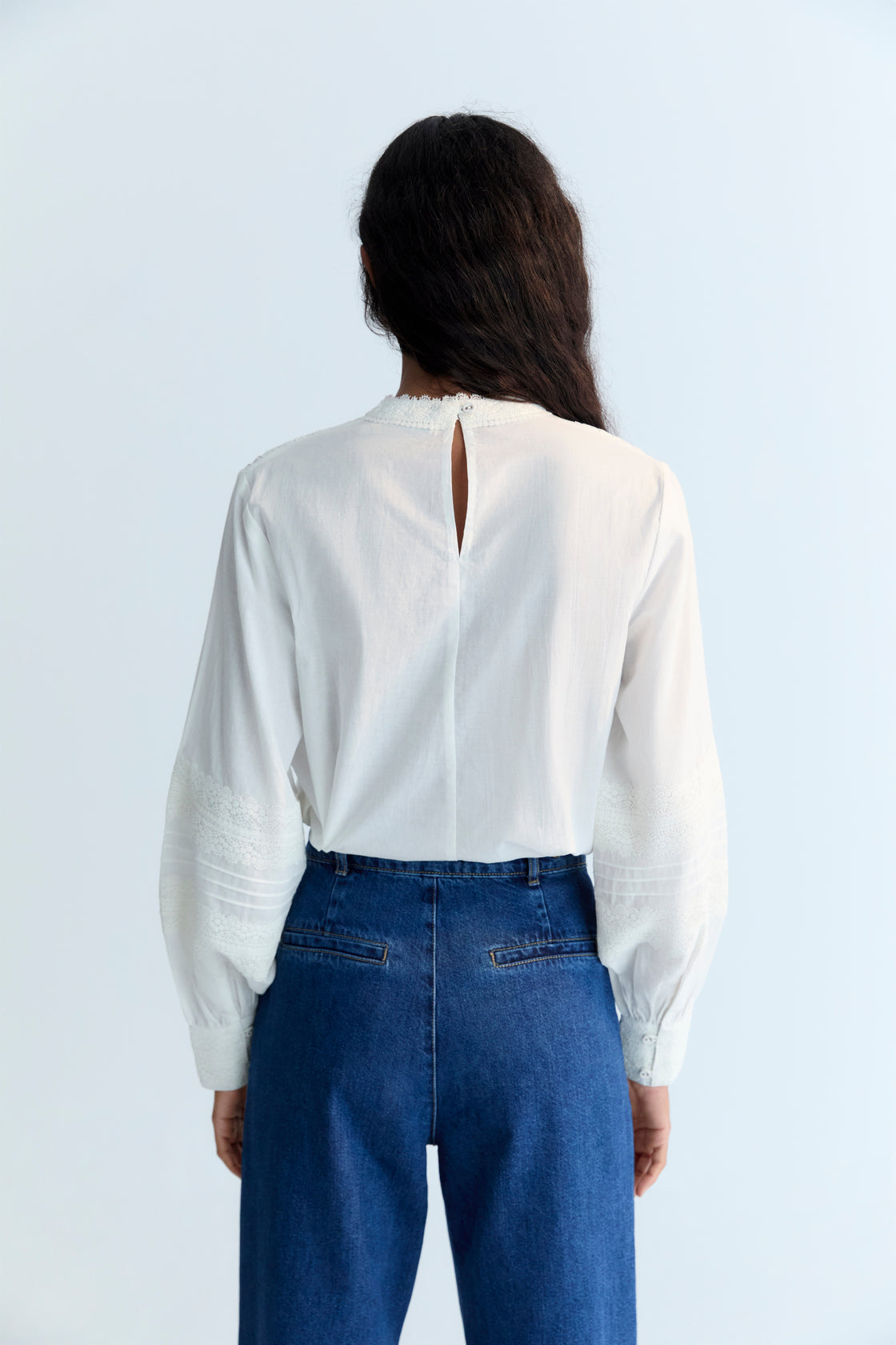 Cambric blouse with elegant lace details at the front and sleeves. It features a back opening with a keyhole and button. Available in two colors.