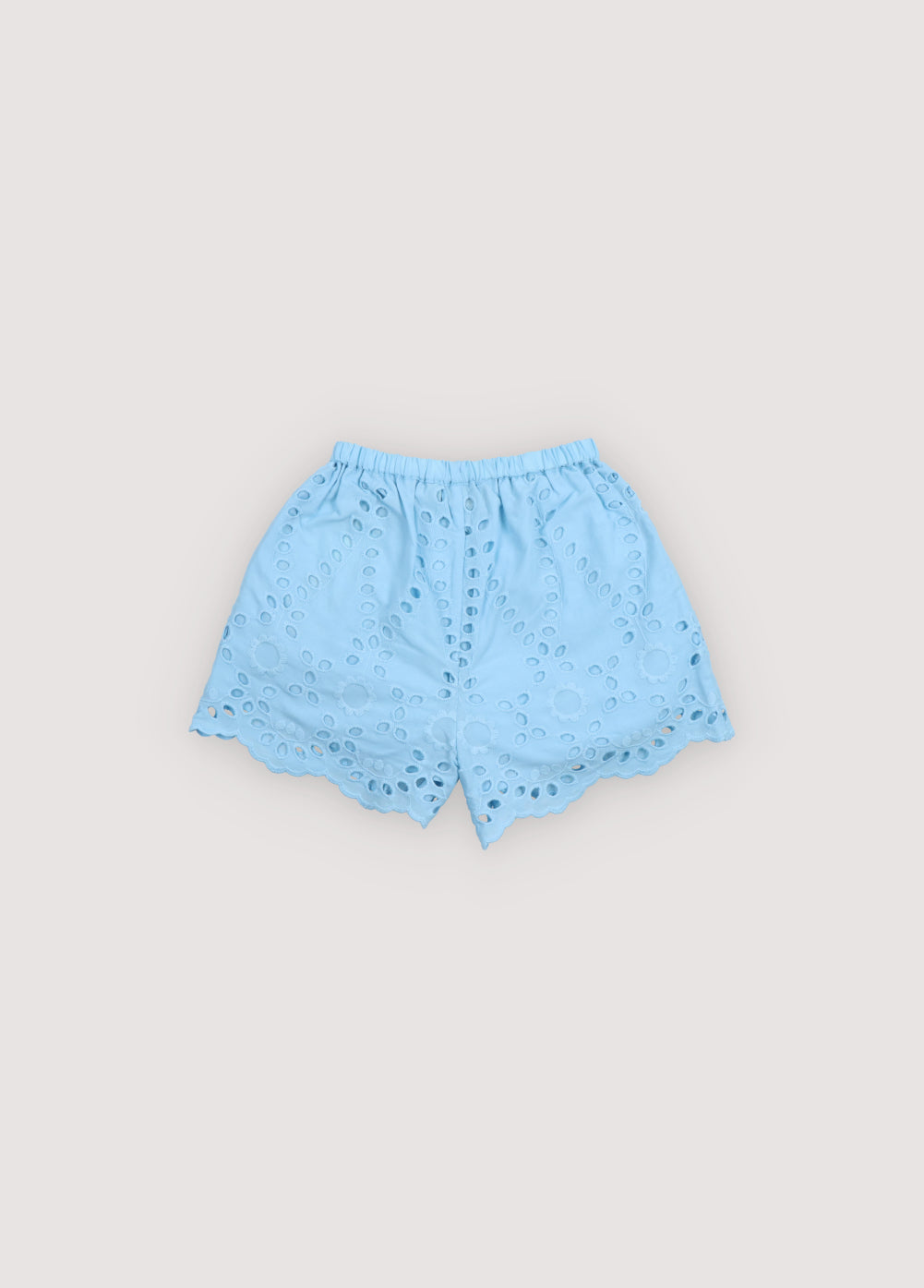 Patmos Short in embroidered voile fabric, 100% cotton, in powder blue color, featuring central buttons, elastic waistband with ruffle detail, and embroidered fabric finishing on the hem. Spring Summer Collection. The New Society.