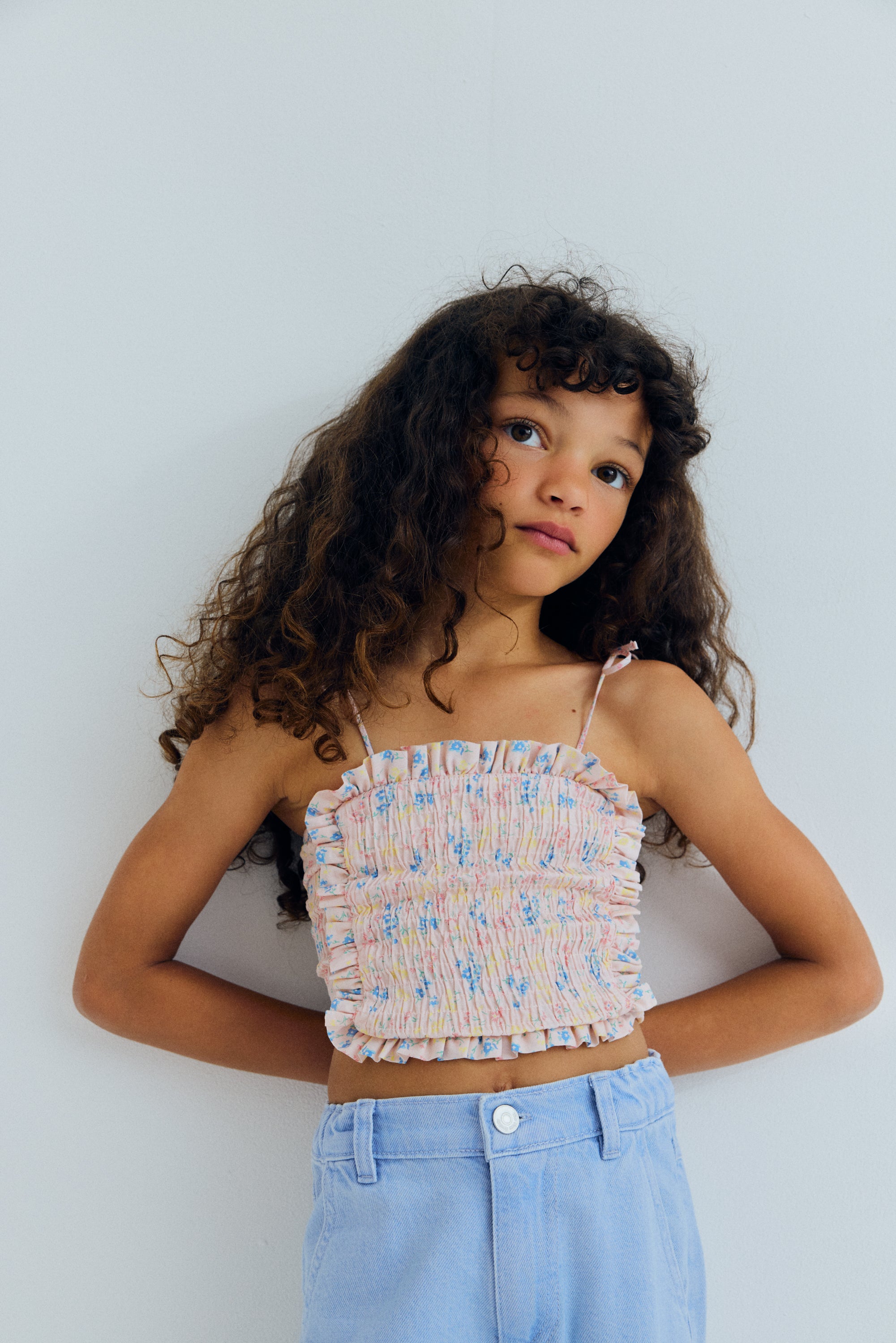 Organic cotton top featuring a smocked bodice for a comfortable, flexible fit and a delicate ruffled hem that adds movement and charm.