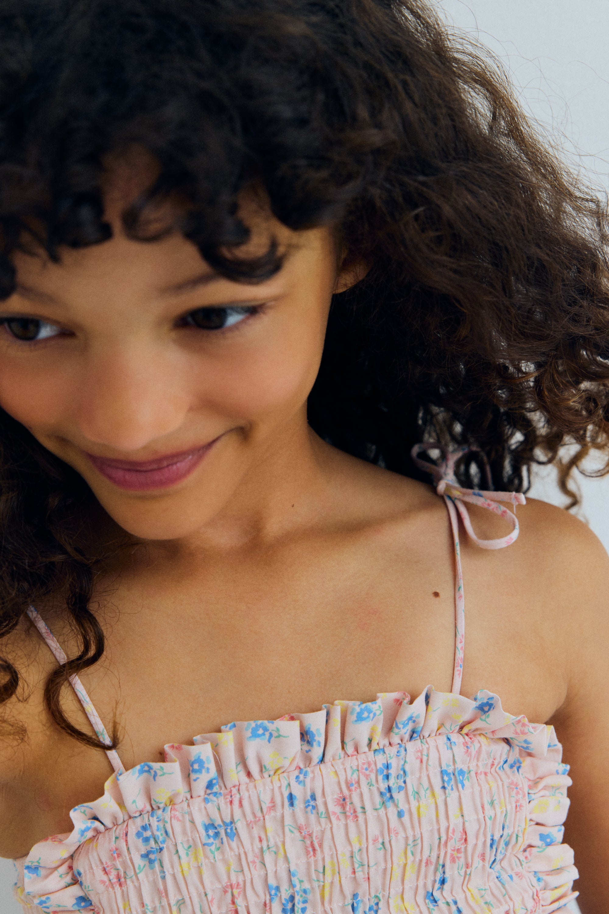 Organic cotton top featuring a smocked bodice for a comfortable, flexible fit and a delicate ruffled hem that adds movement and charm.