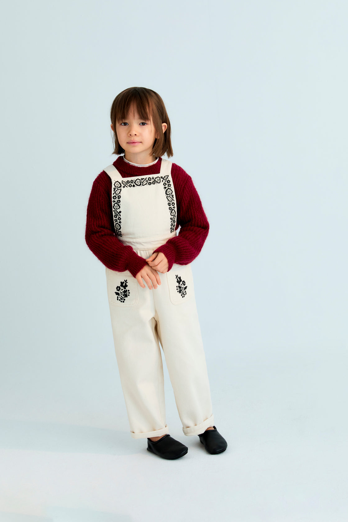 Denim overall with contrast embroidery details on the upper front and two patch pockets in the front. It features an elastic waistband at the back and adjustable straps at the back.