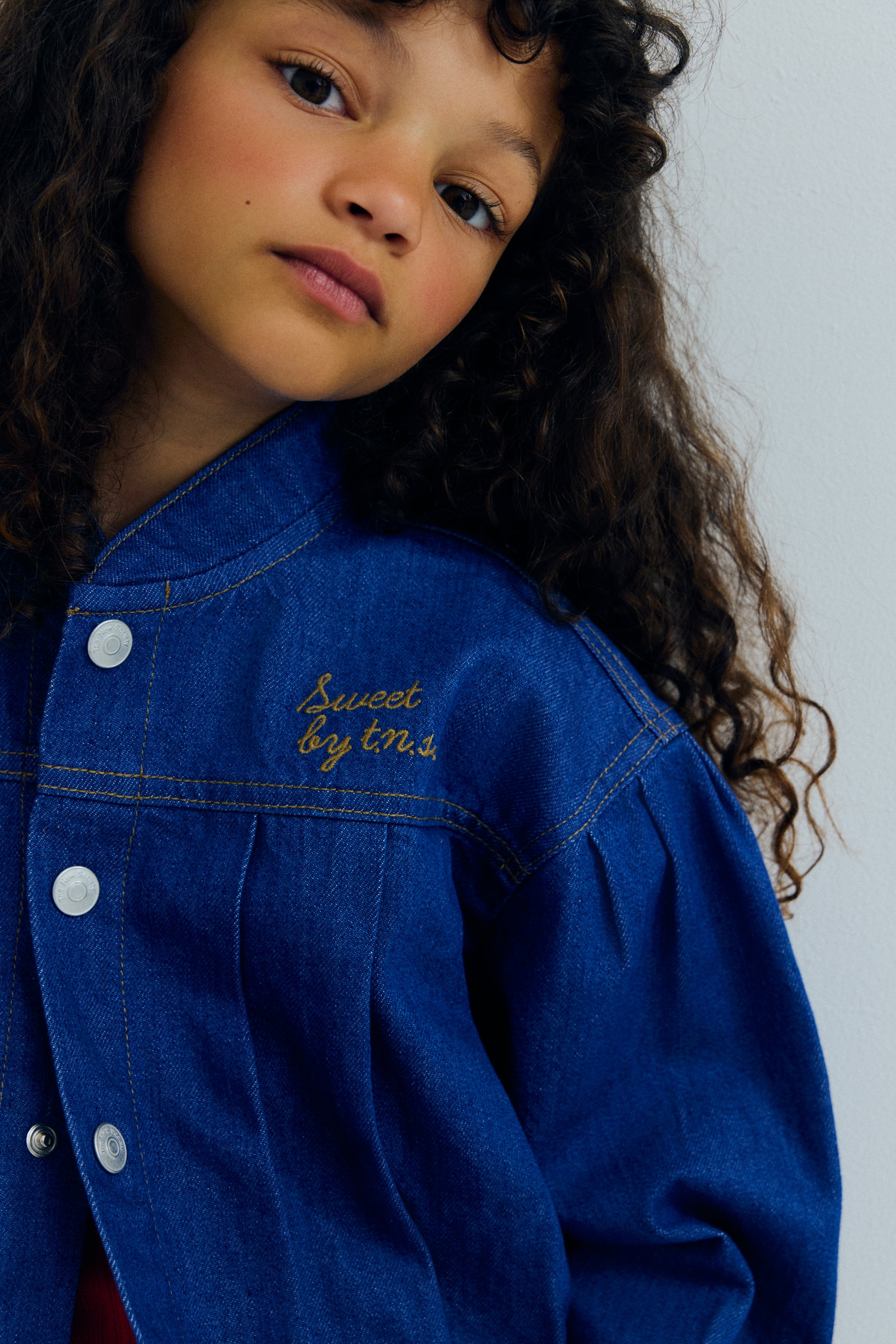 Jeansjacke mit Faltendetails auf Vorder- und Rückseite, Passe und Taschen, die eine strukturierte und dennoch entspannte Silhouette schaffen.