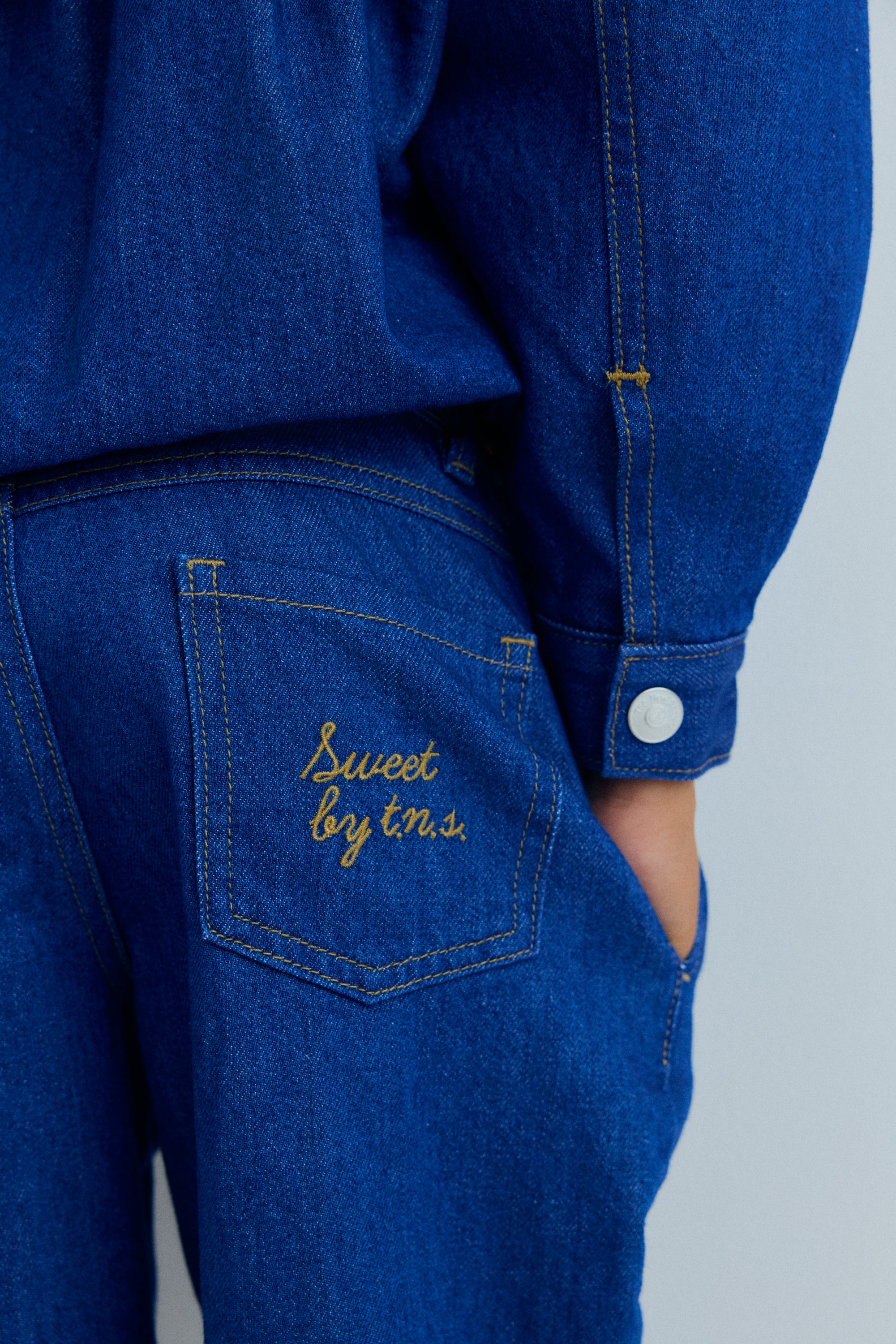 Wide leg denim trousers with front pleats that enhance the relaxed silhouette.