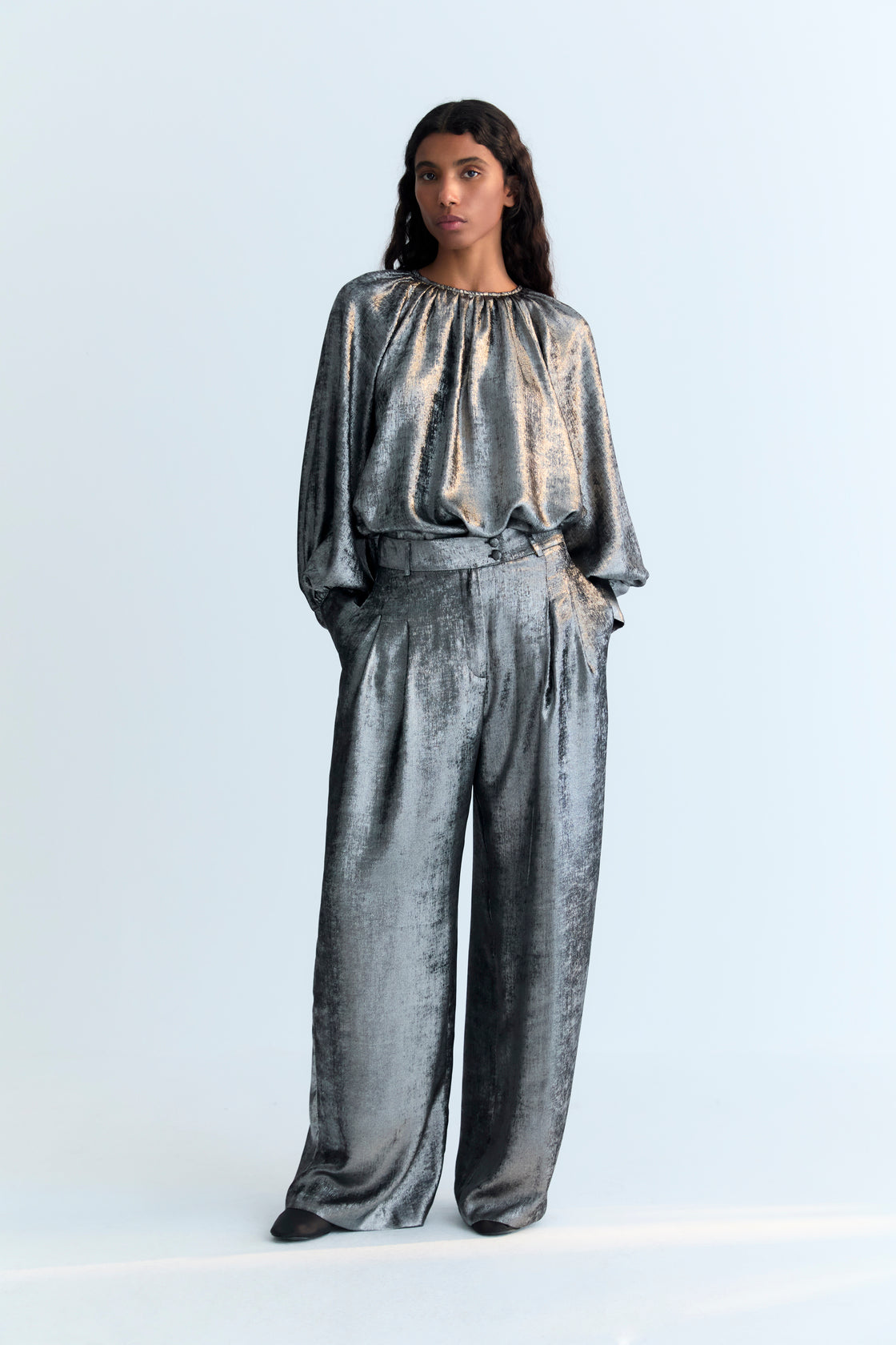 Straight pants in silver shine fabric with front pleat detailing, pockets, and a crossover waistband with a hidden button.