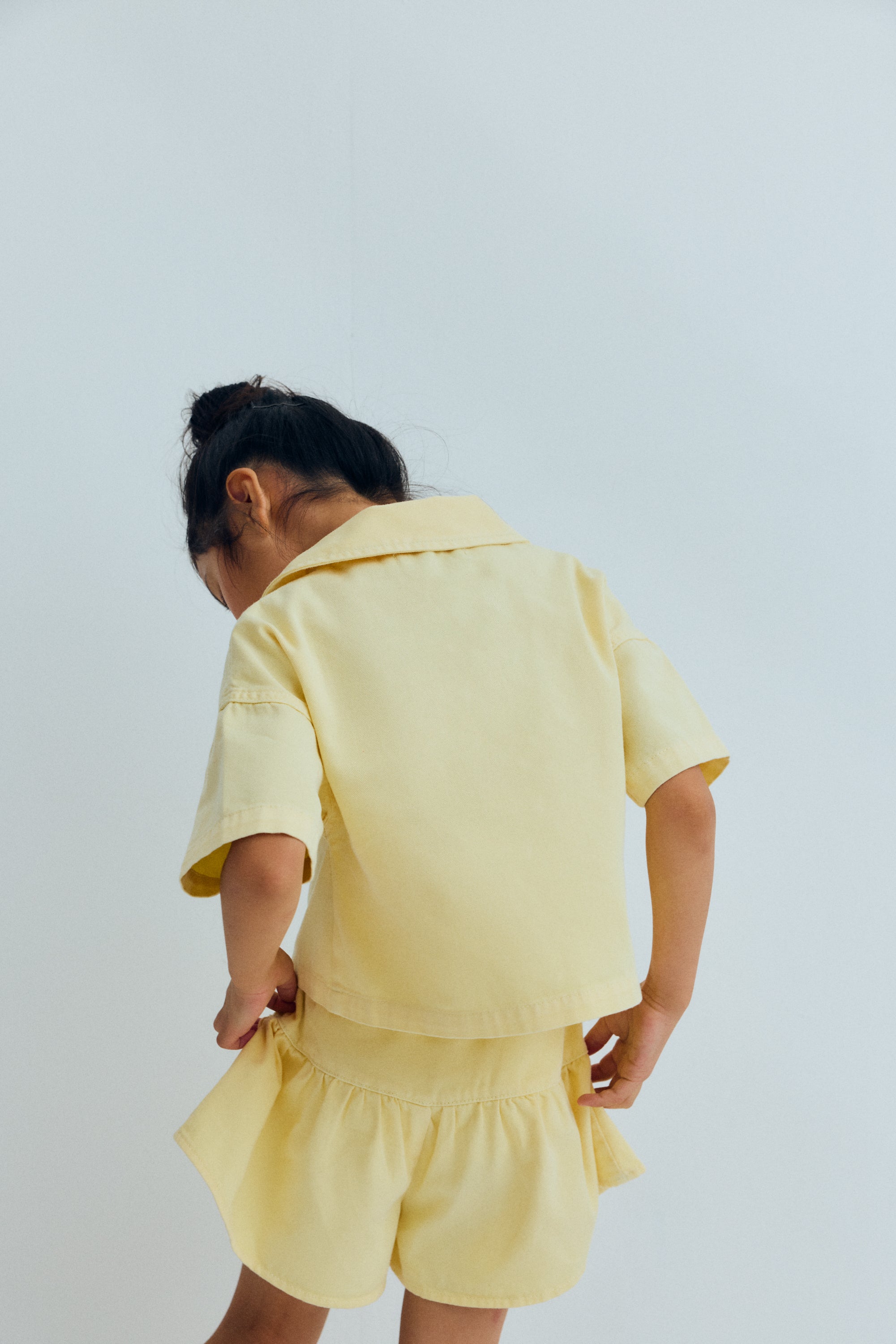 Washed denim shorts with a pointed cut and voluminous leg, featuring delicate ruching for a fresh, playful silhouette. Includes a side zipper and TNS heart embroidery on the side, perfect for a fun and stylish look.